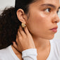 ECLIPSE hoops gold-plated earrings on a woman's ear, showcasing their organic, nature-inspired design with a stylish flair.