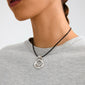 Close-up of a person wearing the UNFOLD necklace silver-plated by Pilgrim, showcasing its chunky, artistic silver pendant on a black cord against a light-gray top.