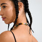Close-up of a person wearing the UNFOLD necklace by Pilgrim, featuring multicolored chunky beads and a silver-plated clasp, styled with a black-strap top.