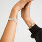 Silver-plated SHIFT bracelet on tattooed arm, featuring textured, irregular coins and chain links, embodies Pilgrim's boho-chic sophistication and Scandinavian craftsmanship.