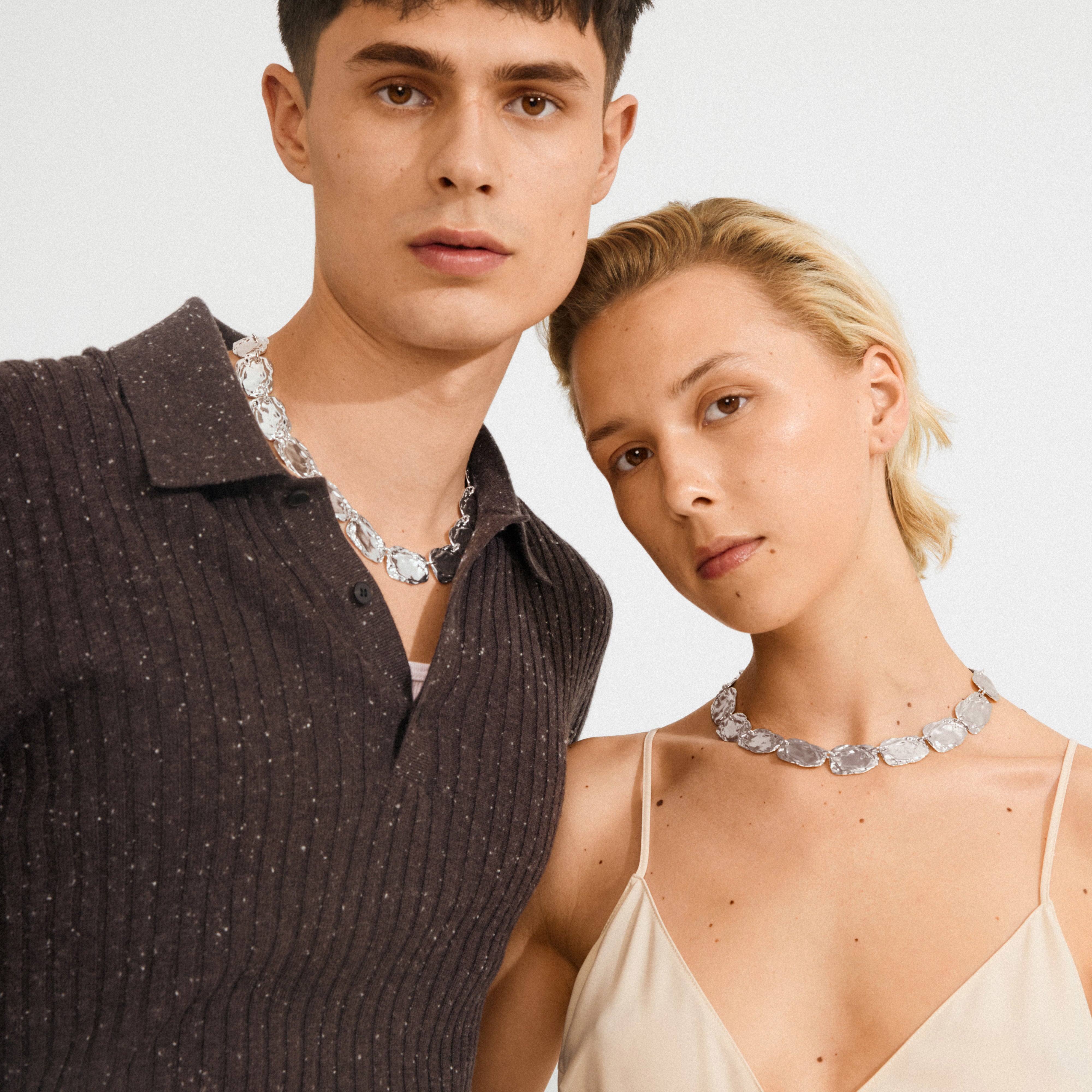 Young man and woman wearing Pilgrim's silver-plated SHIFT necklace, featuring chunky, irregular stone-like links for a bold, stylish look.