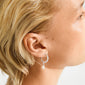 Close-up of a person's ear wearing Pilgrim's SHIFT pearl earrings, featuring a silver-plated hoop with a textured finish and a removable freshwater pearl drop.