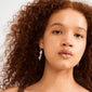 Young person with curly auburn hair wearing Pilgrim's SHIFT hoop earrings, featuring silver charms, Preciosa crystals, and rose quartz, exuding a whimsical, dreamy vibe.
