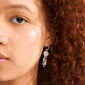 SHIFT hoop earrings, silver-plated, featuring crystal-studded charms with dangling pearls and beads, showcased on a person's cheek and auburn hair.