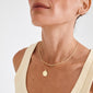 Close-up of the NOMAD 2-in-1 coin necklace gold-plated, featuring a curb chain and a coin pendant chain, worn on a ribbed tank top.