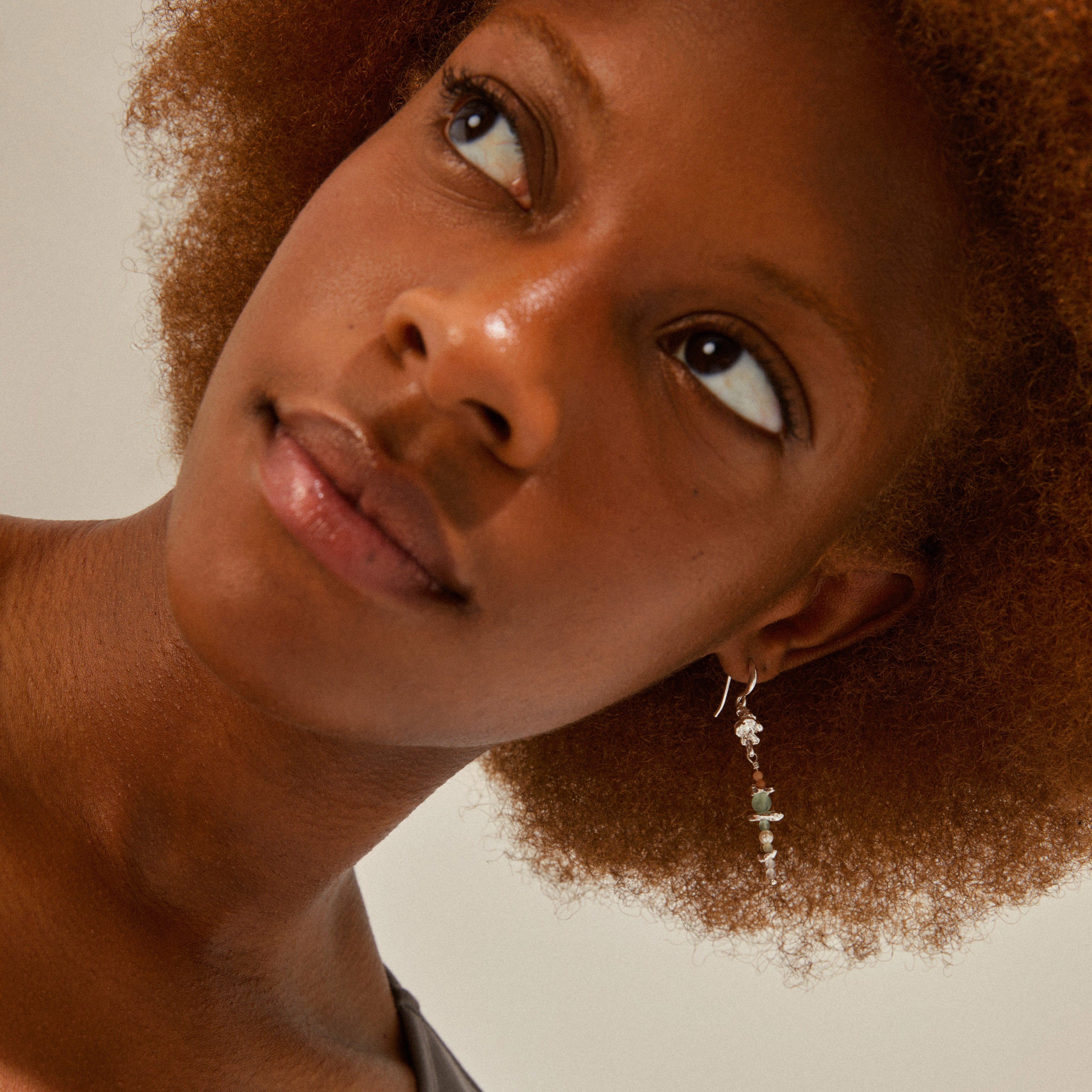Woman wearing CLOUD earrings, featuring silver-plated details with Aventurine, New Jade, and Rose Quartz stones, showcasing a boho and earthy vibe.