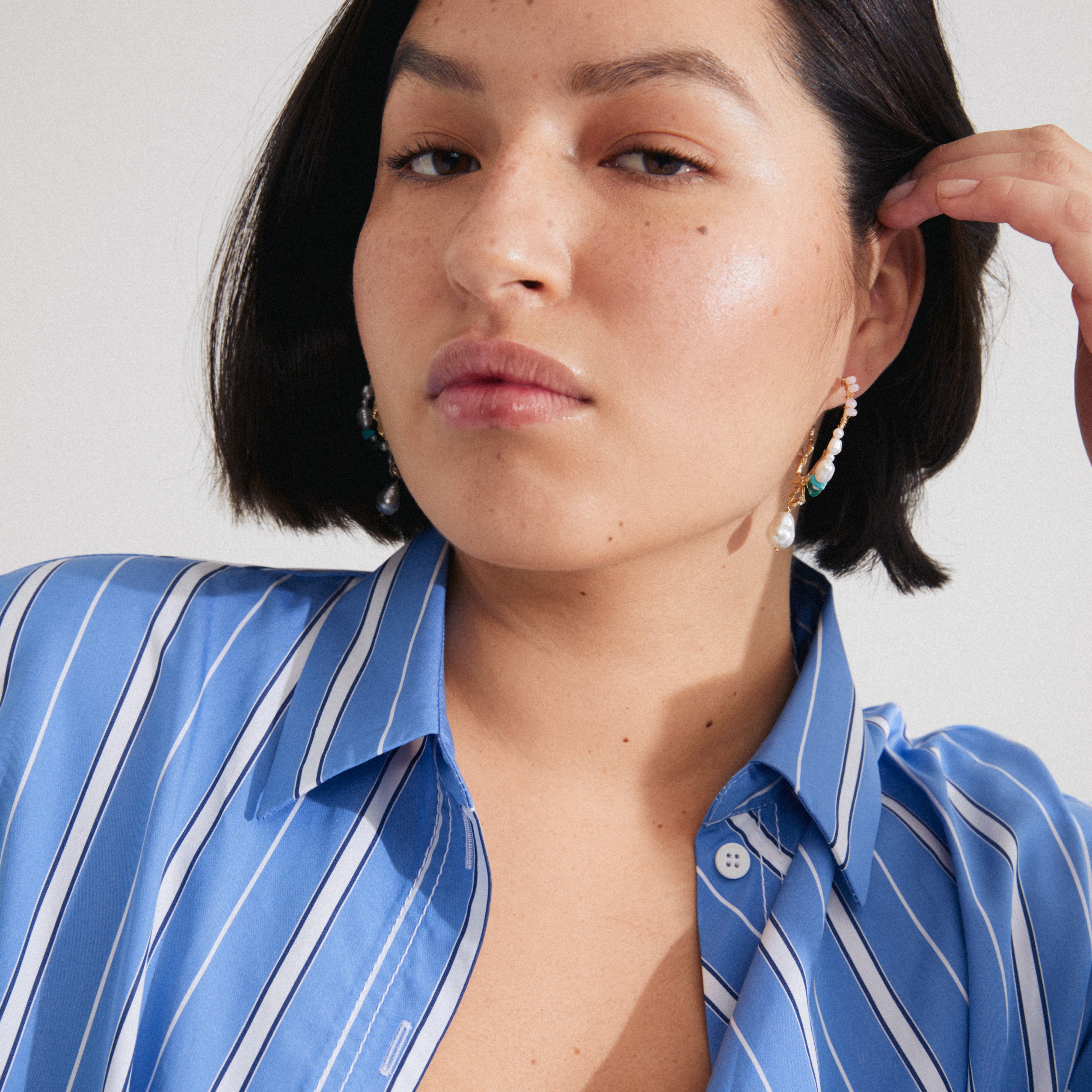 Woman wearing FORCE large hoop earrings with genuine freshwater pearls, turquoise, and South African Jade, showcasing gold-plated details from Pilgrim’s collection.