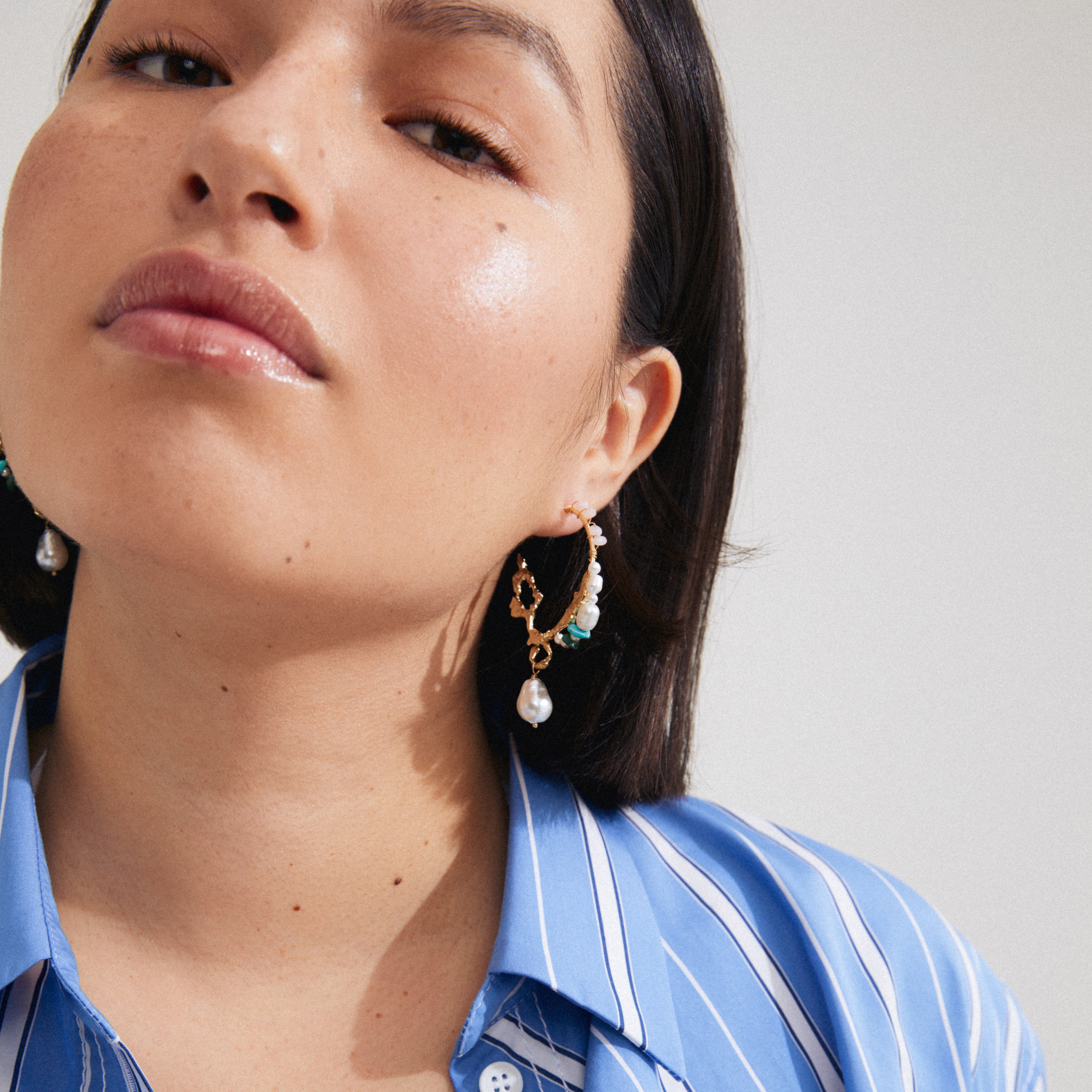 Woman wearing FORCE large hoop earrings by Pilgrim, featuring genuine freshwater pearls and gold-plated details, showcasing a bohemian and luxurious style.