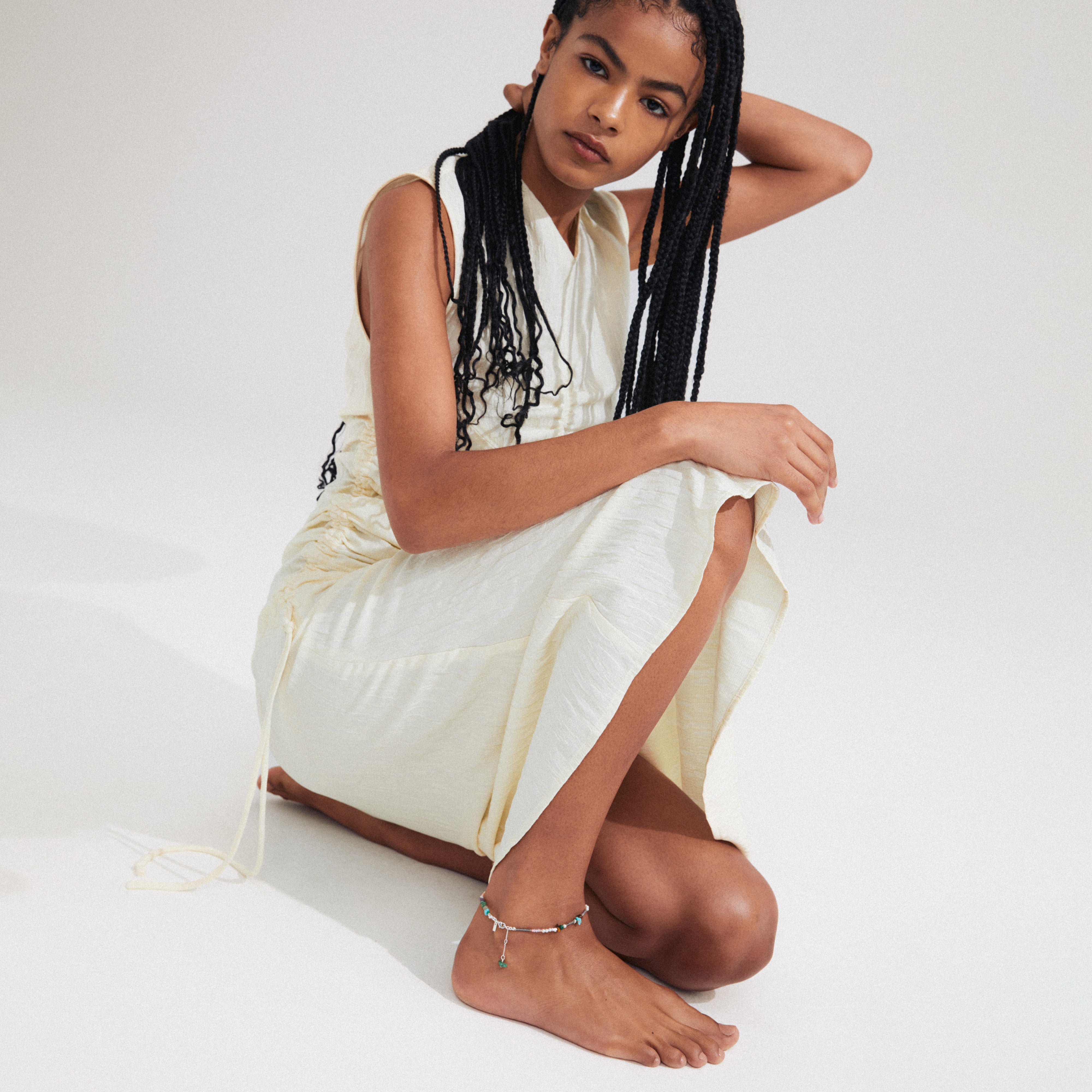 Woman wearing Pilgrim's FORCE anklet, featuring semi-precious stones and silver-plated details, showcasing a boho-inspired style.