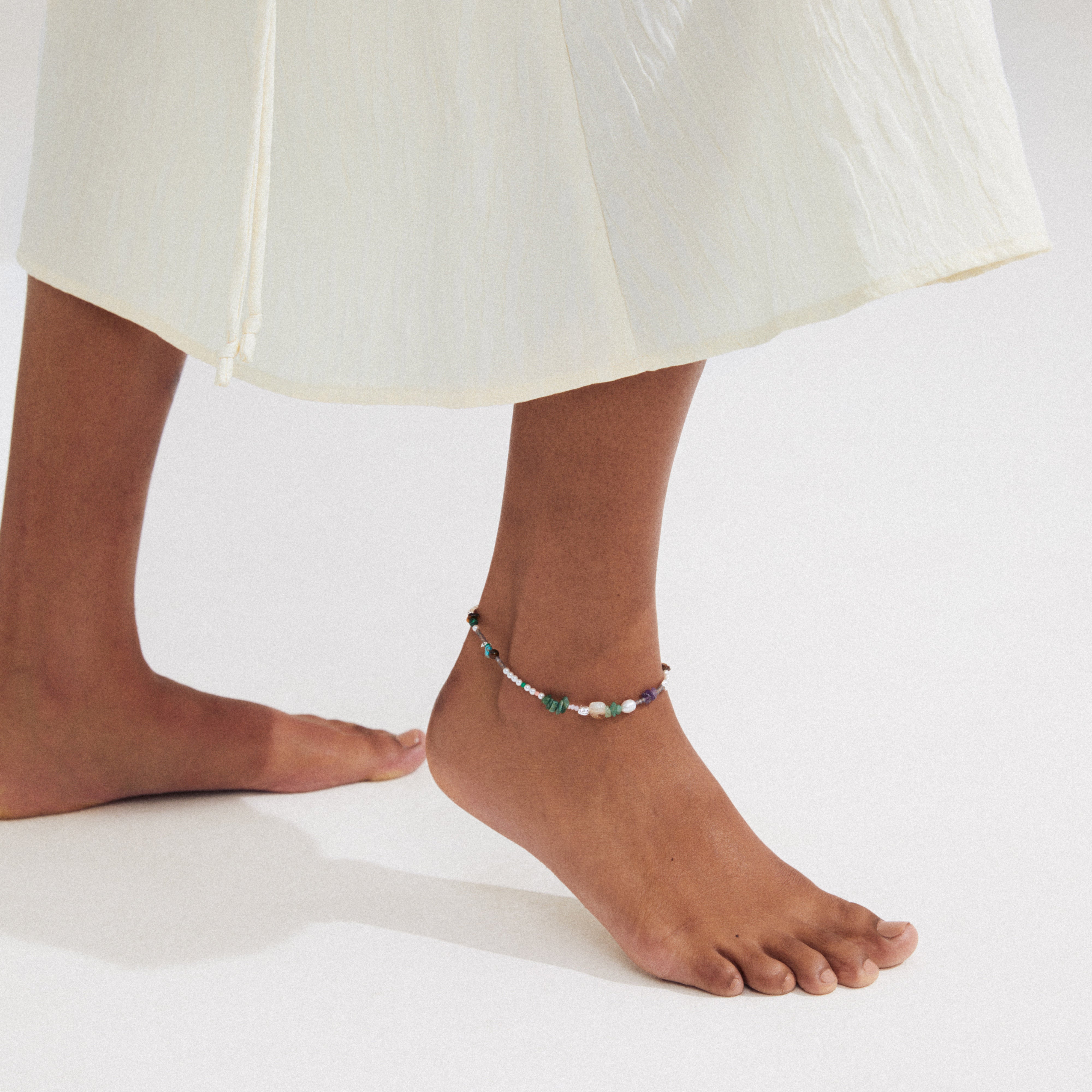 FORCE ankle chain multi/silver-plated, featuring semi-precious stones and freshwater pearls, adorns a foot, exuding a boho-inspired, laid-back summer vibe.