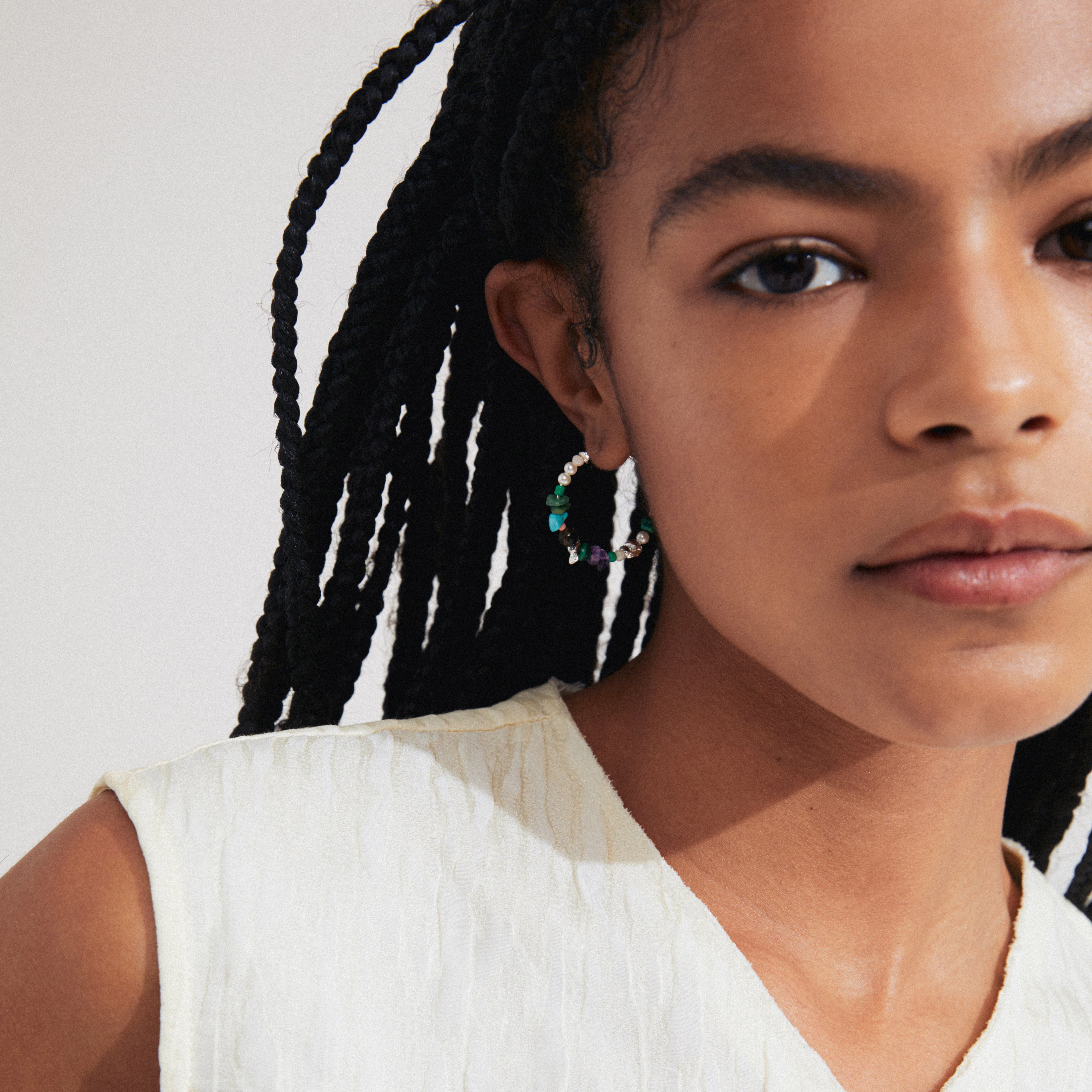 Woman wearing Pilgrim's FORCE hoop earrings, featuring silver-plated details and semi-precious stones, embodying a boho luxe and beachy style.