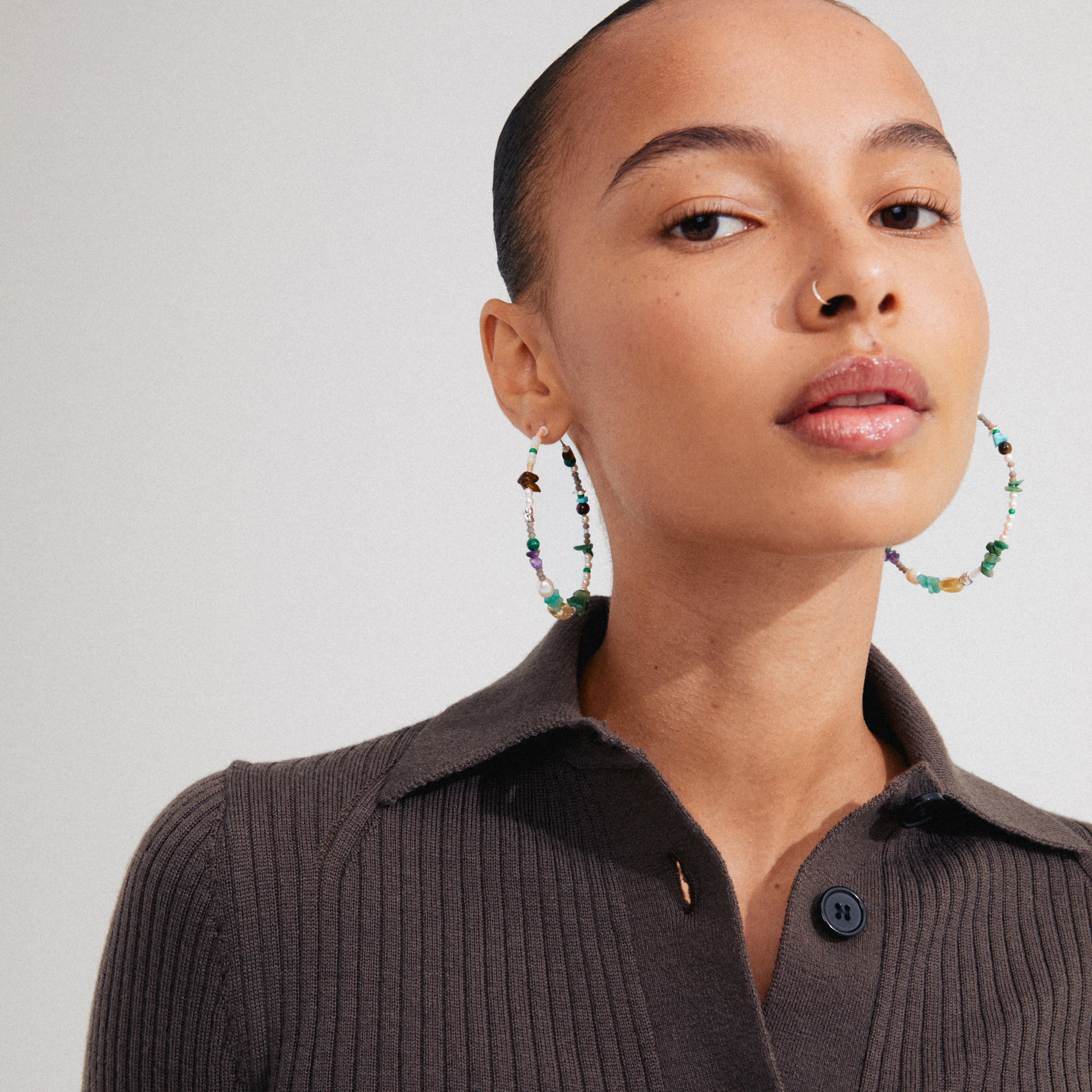 Close-up of FORCE mega hoop earrings with semi-precious stones and silver-plated details, worn by a woman, embodying Pilgrim's trendy and inclusive style.