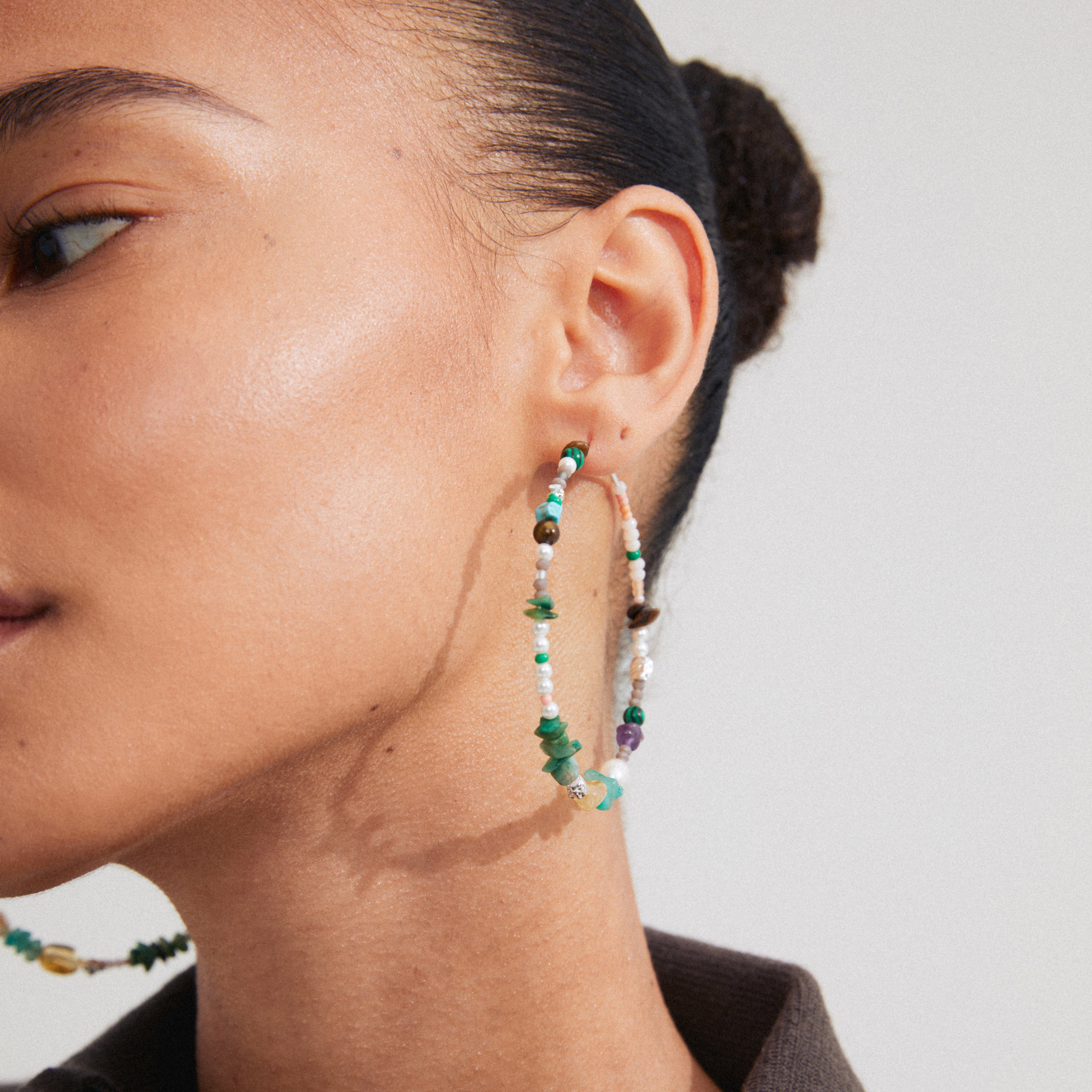 Woman wearing FORCE mega hoop earrings by Pilgrim, featuring semi-precious stones and silver-plated details, highlighting a stylish, summery look.