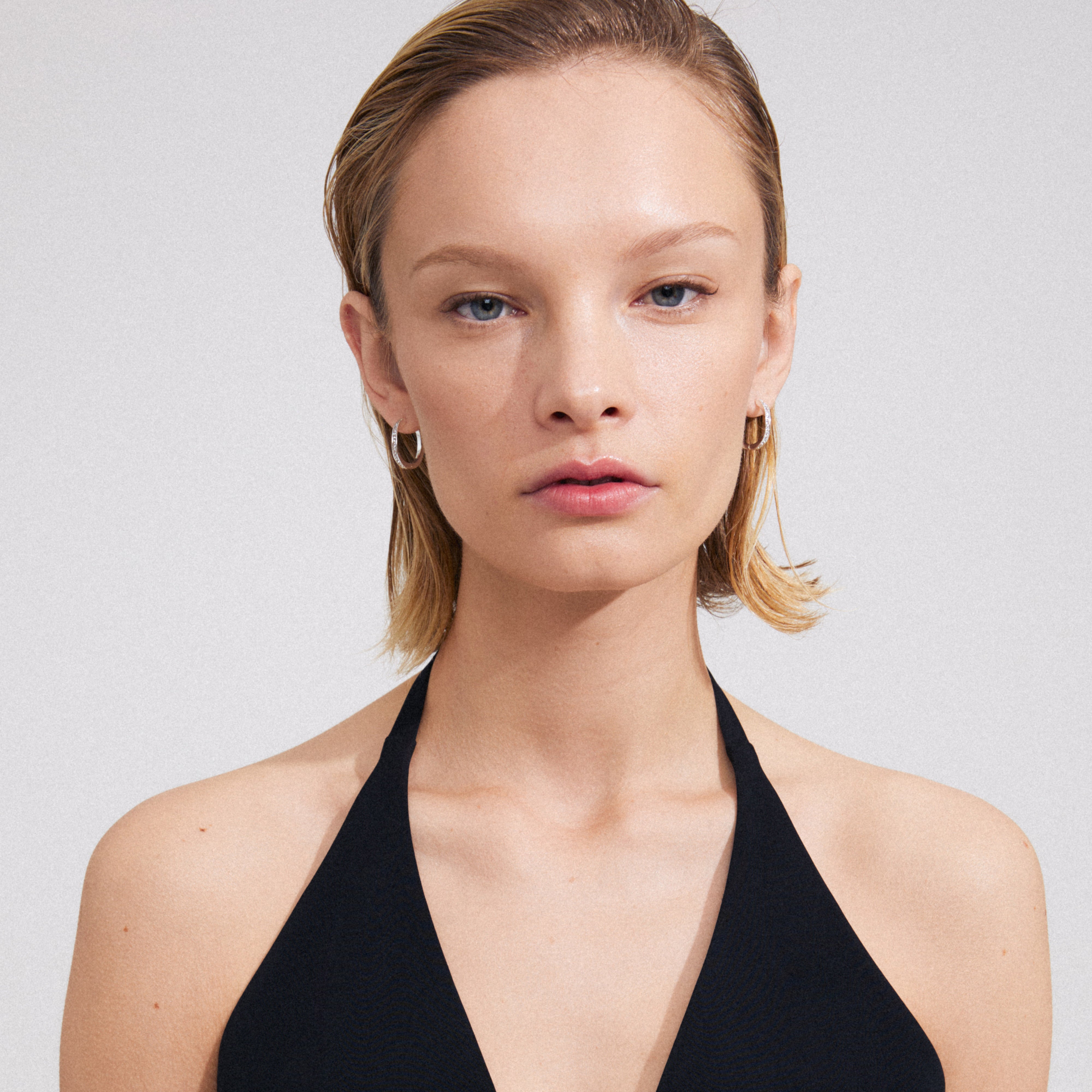 Woman wearing TRUE hoop earrings, silver-plated, with shiny Preciosa crystals and an organic shape, perfect for trendy, effortless looks.