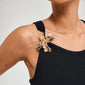 Person wearing a black tank top with DREAM hair-accessory, a gold-plated abstract flower brooch on the strap, showcasing its striking design and eco-friendly craftsmanship.