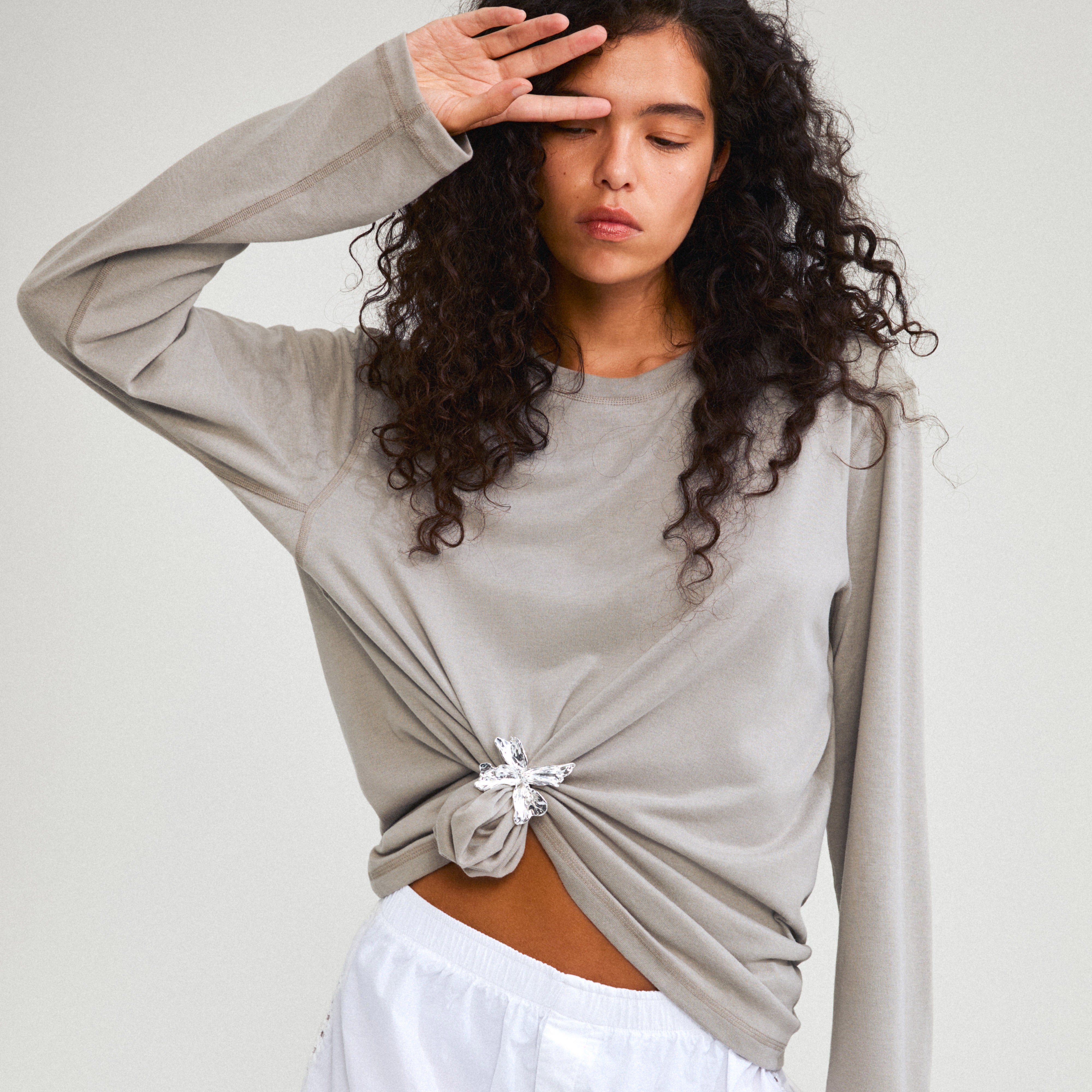 Young woman styles her outfit with the DREAM hair-accessory silver-plated, a versatile flower charm pin from Pilgrim, enhancing her casual look with elegance.
