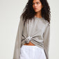 Woman wearing taupe shirt with a DREAM hair-accessory silver-plated, featuring a large flower charm, styled in her hair, adding elegance to her look.