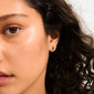Close-up of a woman's face showcasing Pilgrim's BETWEEN gold-plated stud earrings with cabochon-cut Tiger Eye stones, exuding boho chic and vintage elegance.