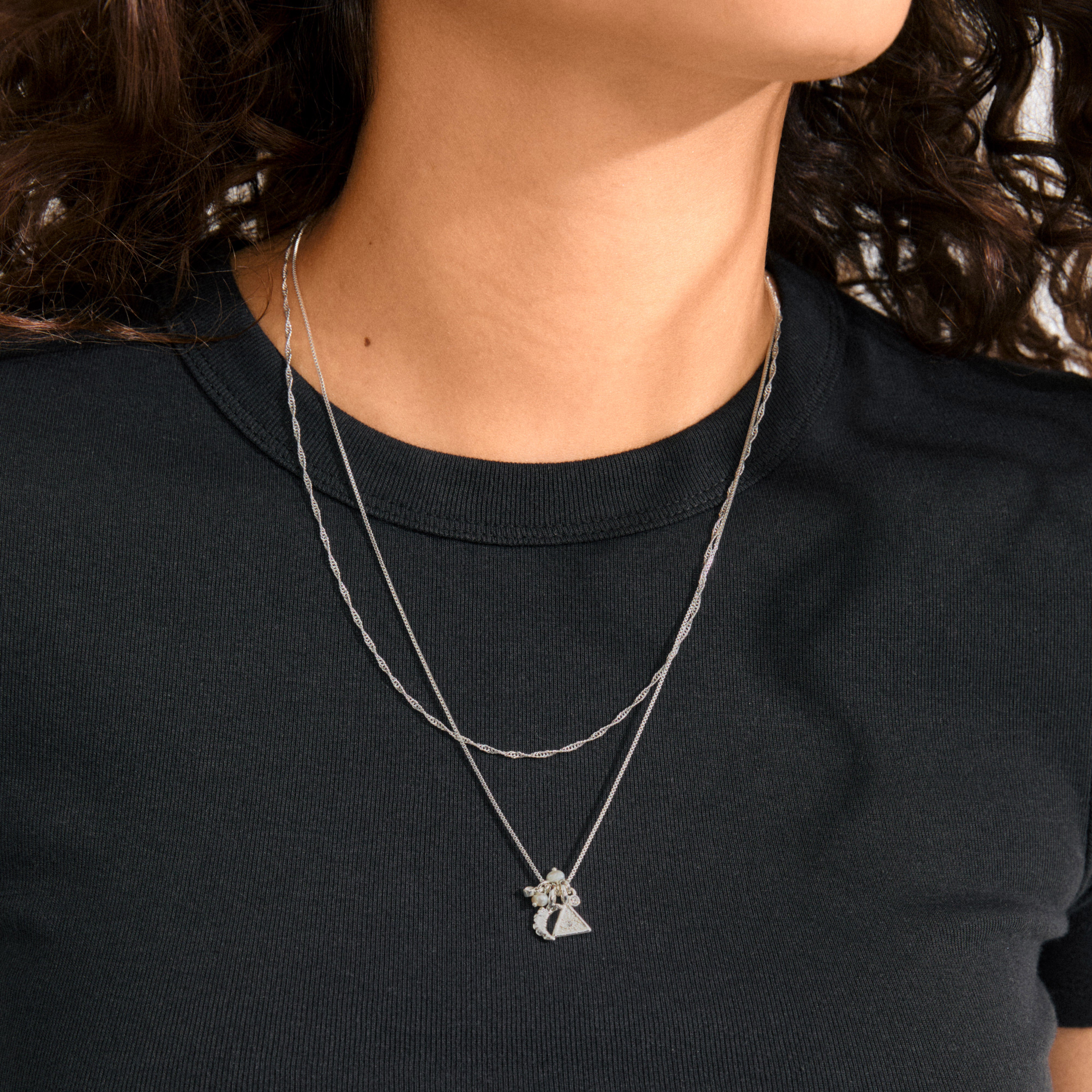 Close-up of the BETWEEN necklace 2-in-1 silver-plated on a woman's neck, featuring a box chain and twisted chain with pendants, embodying bohemian magic.
