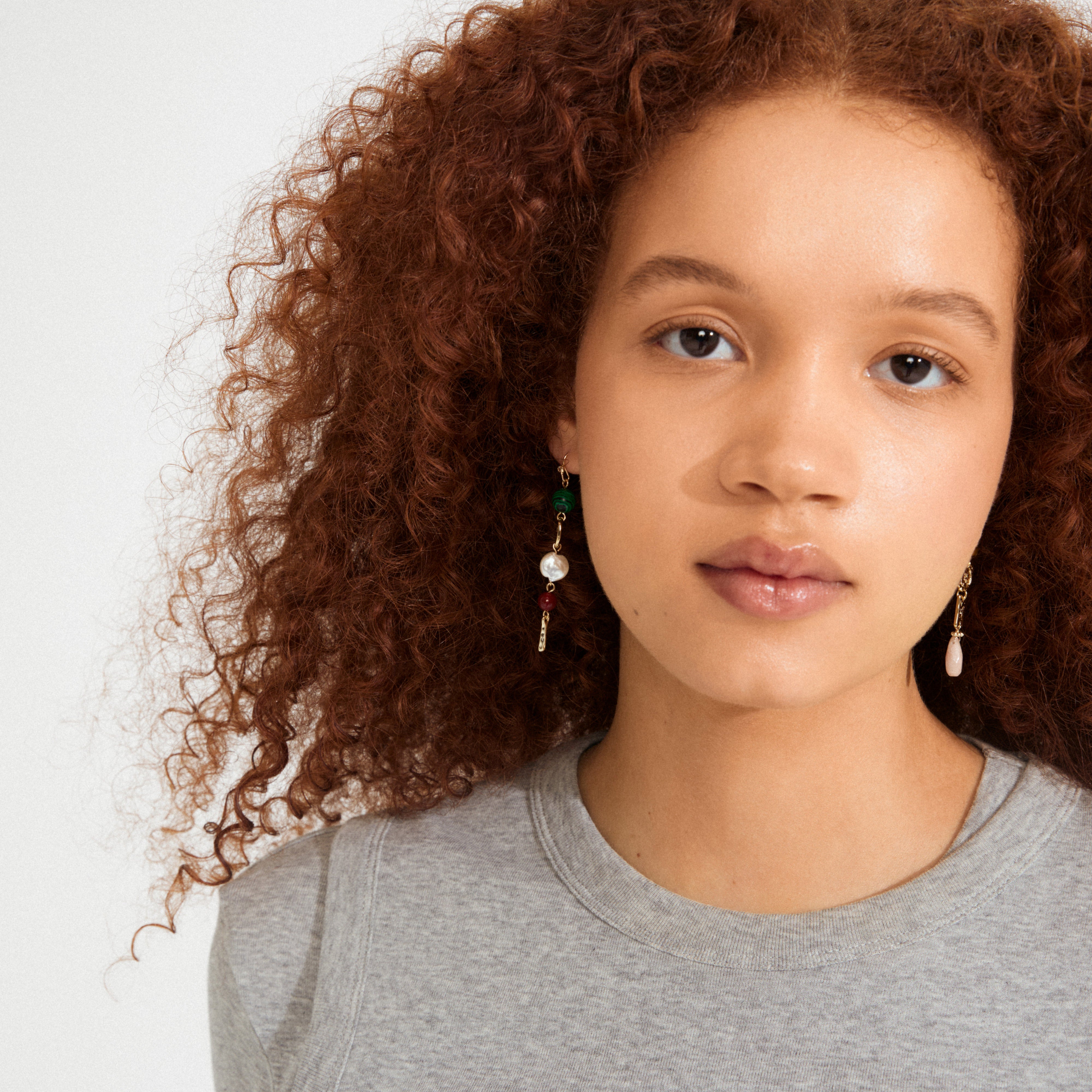 Close-up of the gold-plated SENSE earrings by Pilgrim, featuring an asymmetrical design with colorful beads for a playful, bohemian touch.