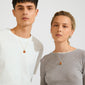 Two young adults showcase Pilgrim's SENSE necklace, featuring a gold-plated chain with a round Red Agate pendant, embodying strength and creativity.