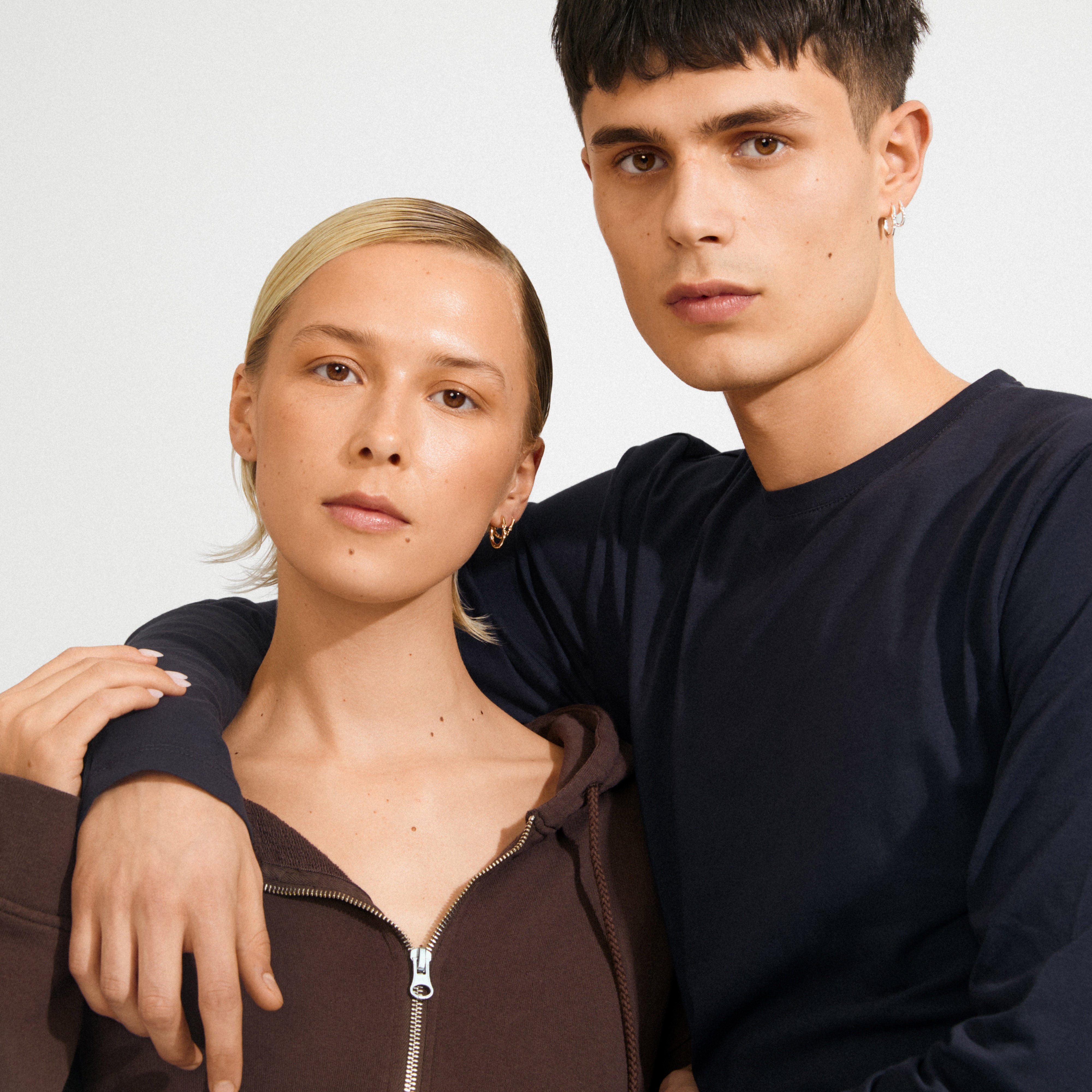Two young adults model SENSE hoop earrings, 2-in-1 set, silver-plated, showcasing their sleek, nature-inspired design and versatile, minimalist styling.