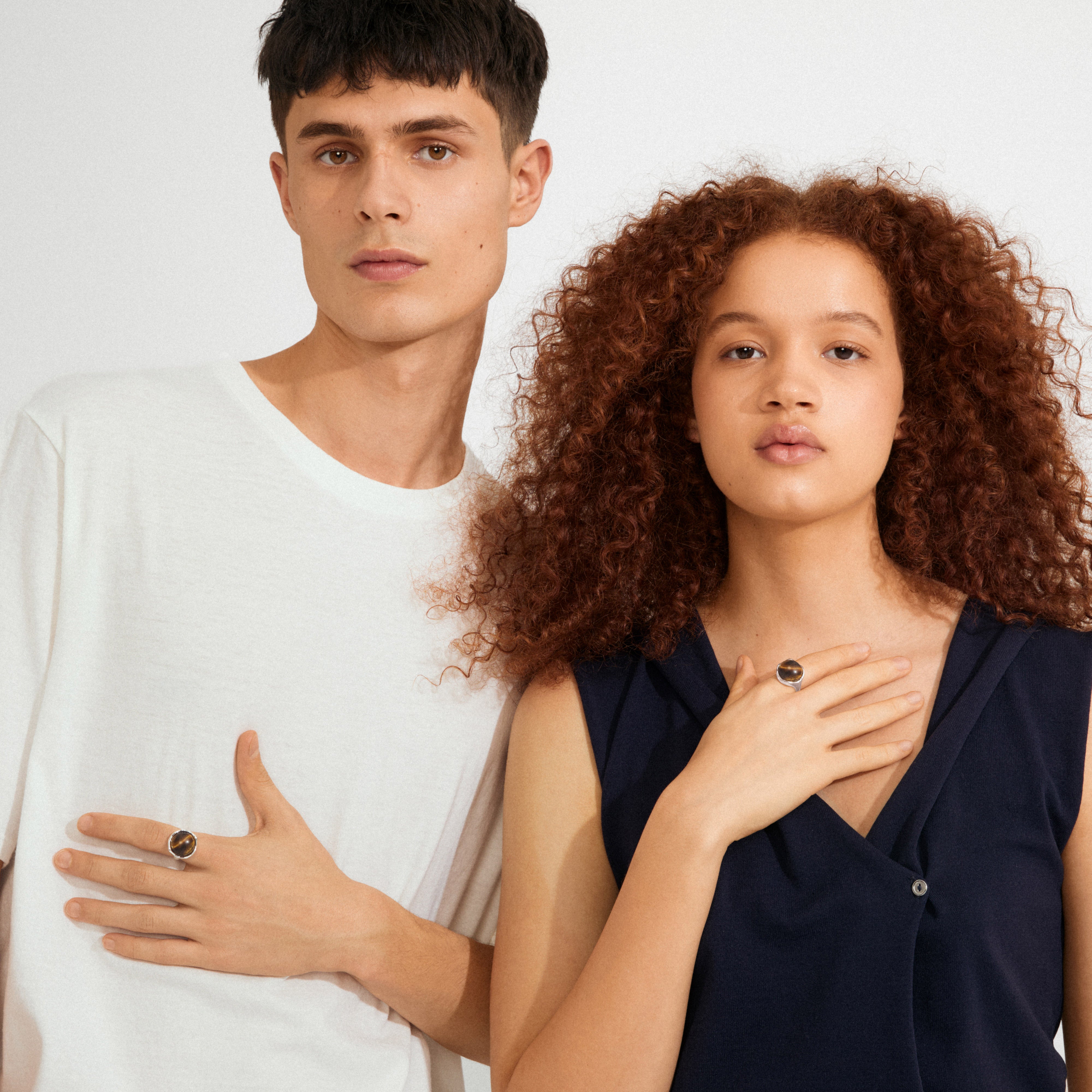Two young models showcase the Pilgrim SENSE ring, featuring a silver-plated setting with a Tiger Eye stone, symbolizing strength and confidence.