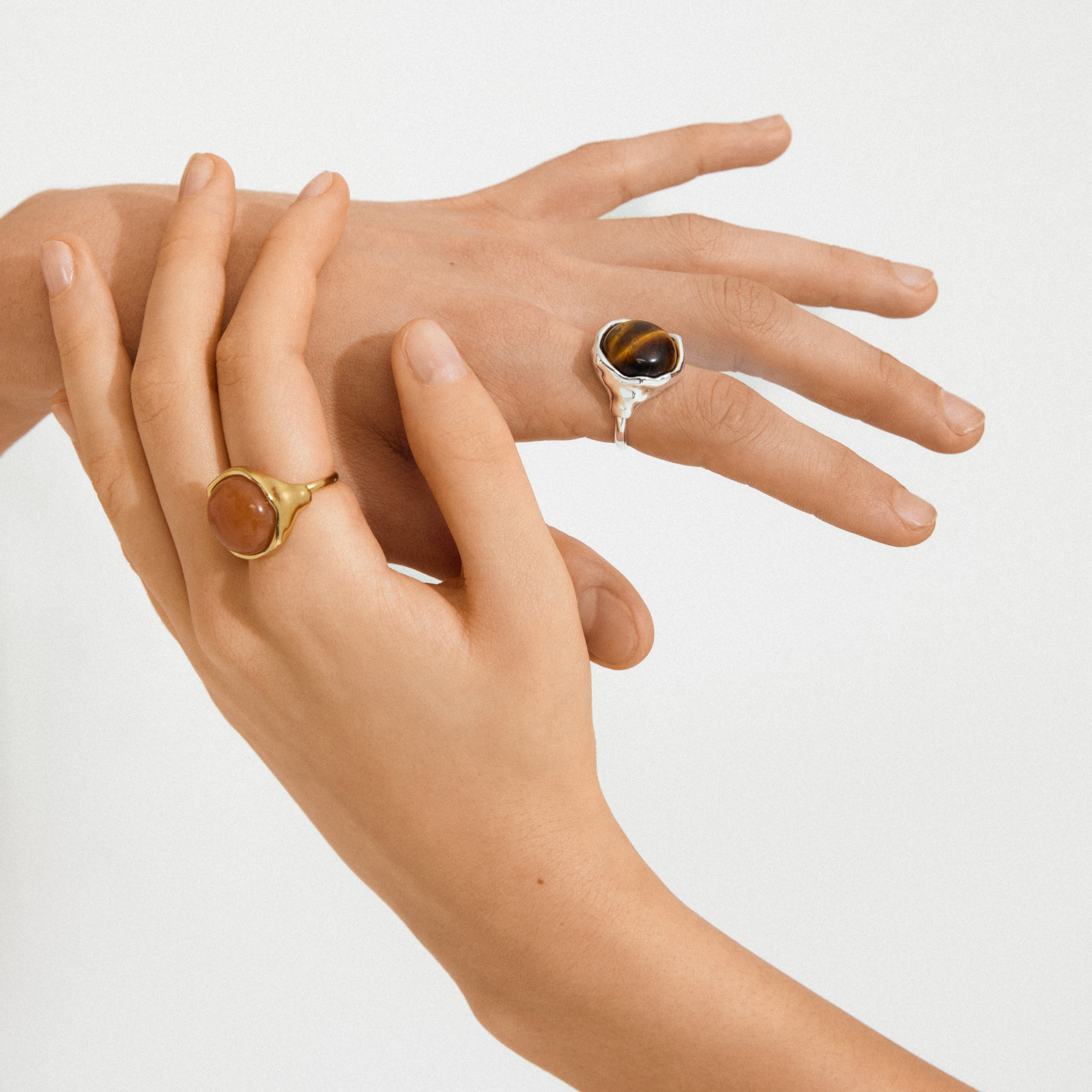 Close-up of hands wearing Pilgrim's SENSE ring, silver-plated with a tiger’s-eye gemstone, showcasing its bold, sculptural design and shimmering beauty.