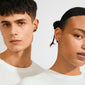 Two young adults wearing SENSE earrings by Pilgrim, showcasing silver-plated settings with Tiger Eye stones, symbolizing strength and balance, against a simple backdrop.