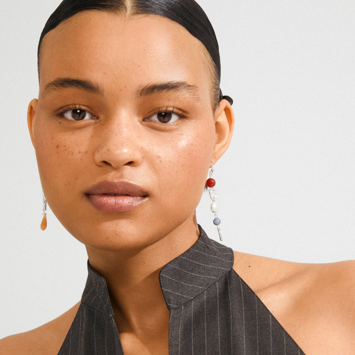 Young woman wearing Pilgrim's SENSE earrings, featuring asymmetrical silver-plated drops with colorful beads, highlighting a boho luxe style.