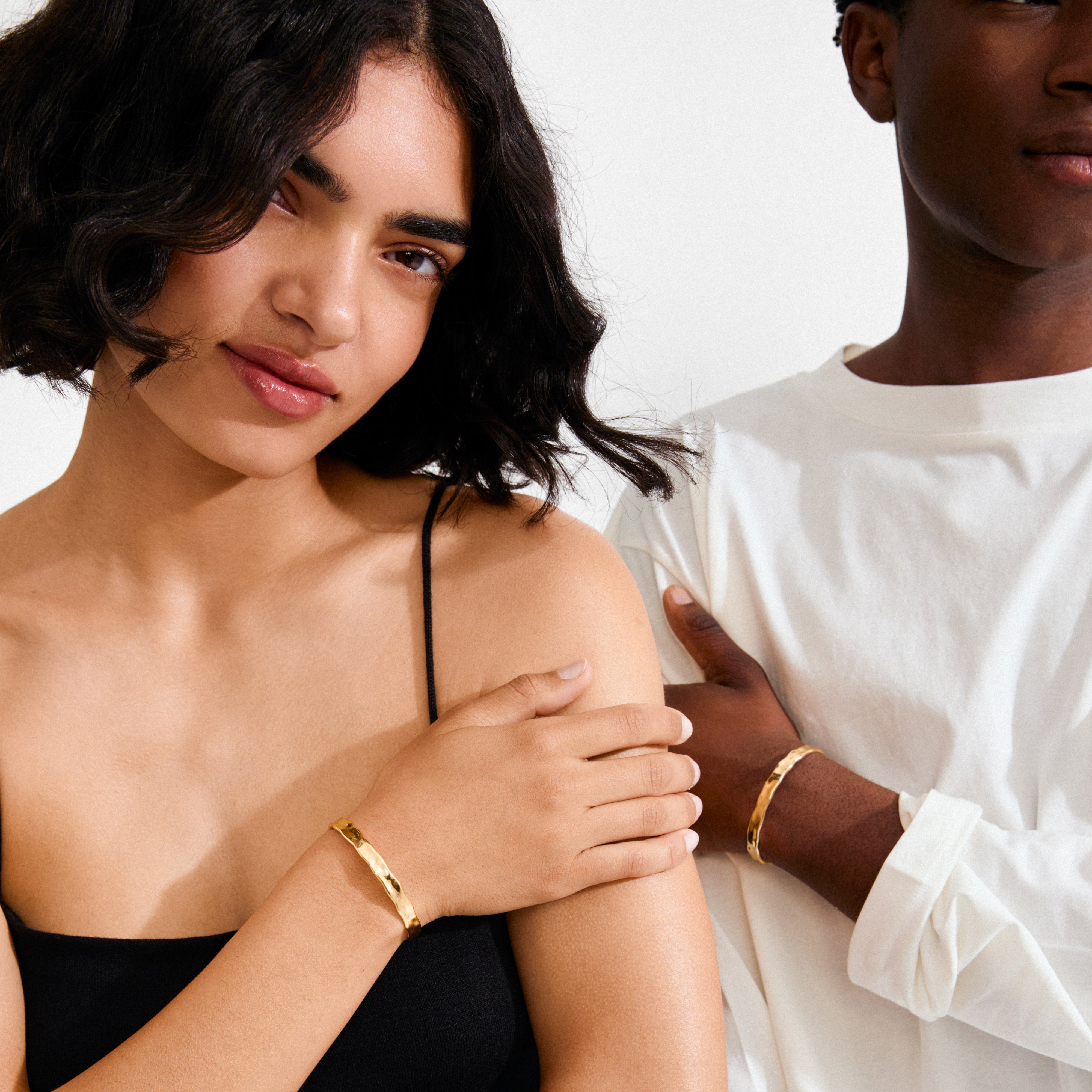 Models showcase Pilgrim's EMBER gold-plated bangles, featuring sculptural, hammered texture for a minimalist yet bold Scandinavian style.