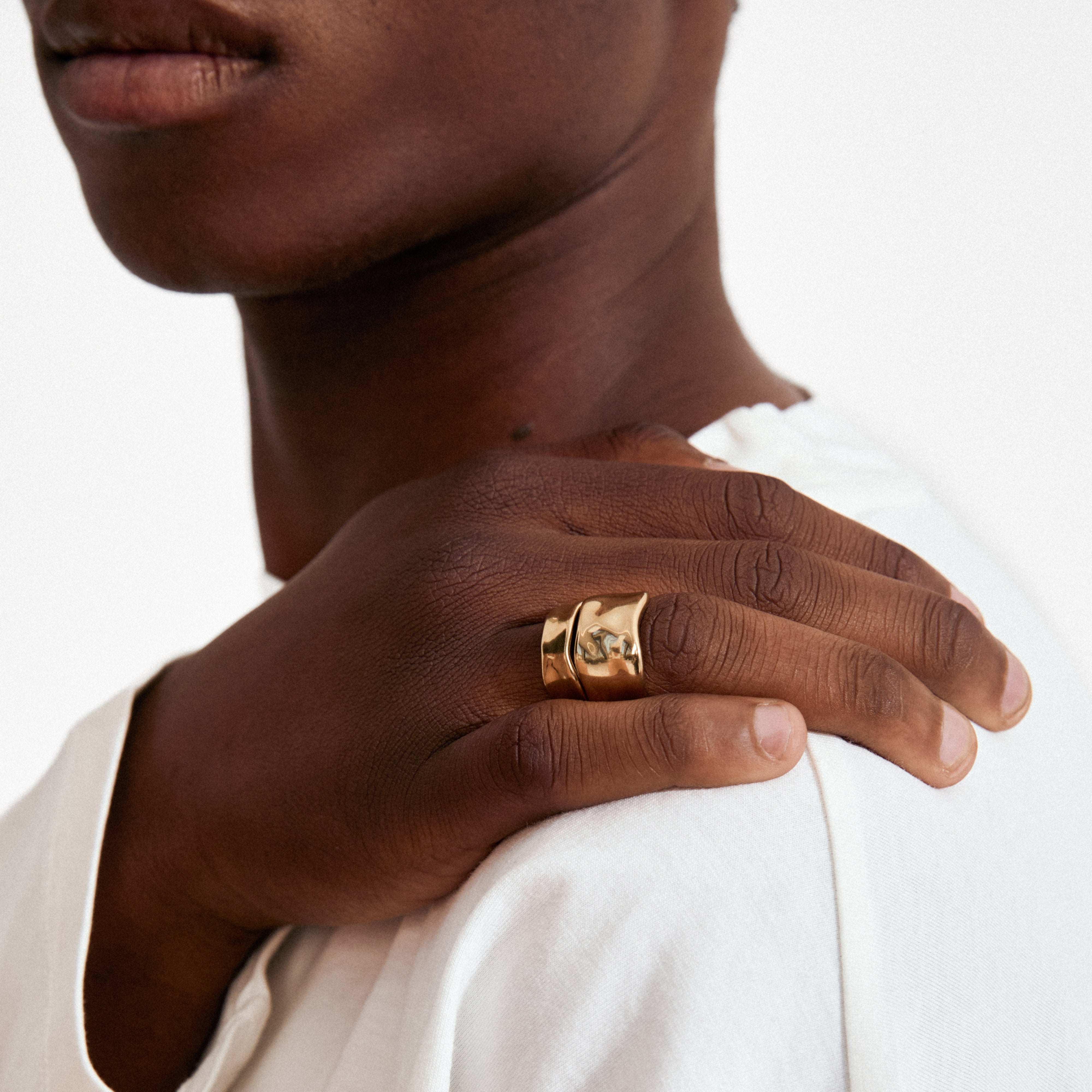 Close-up of a hand wearing Pilgrim's EMBER rings 2-in-1 set, showcasing the chunky, gold-plated, sculptural design on a finger with textured detail.