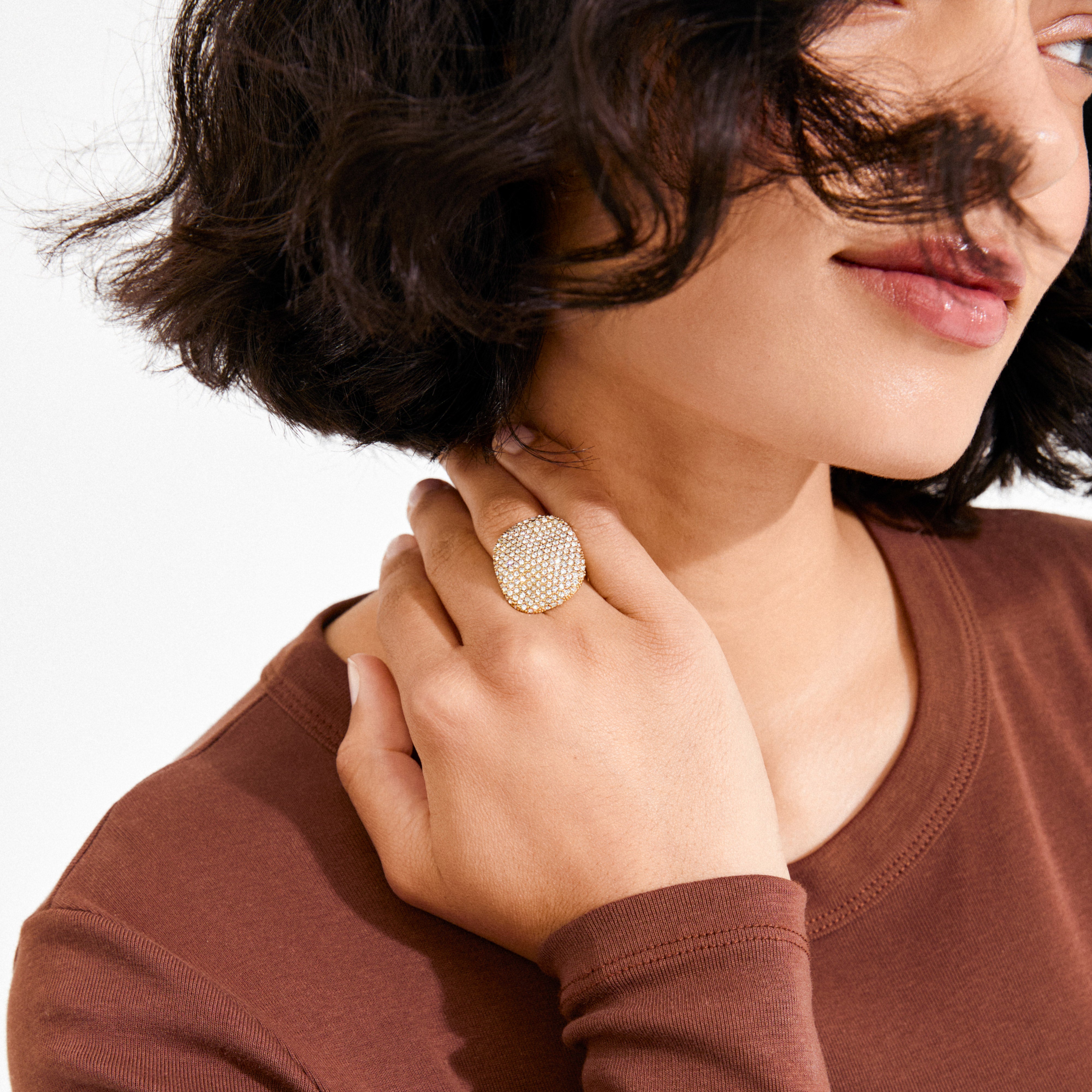 Woman wearing the EMBER ring gold-plated, a pavé-style cocktail ring with sparkling stones, highlighting its bold, wavy square centerpiece and adjustable fit.