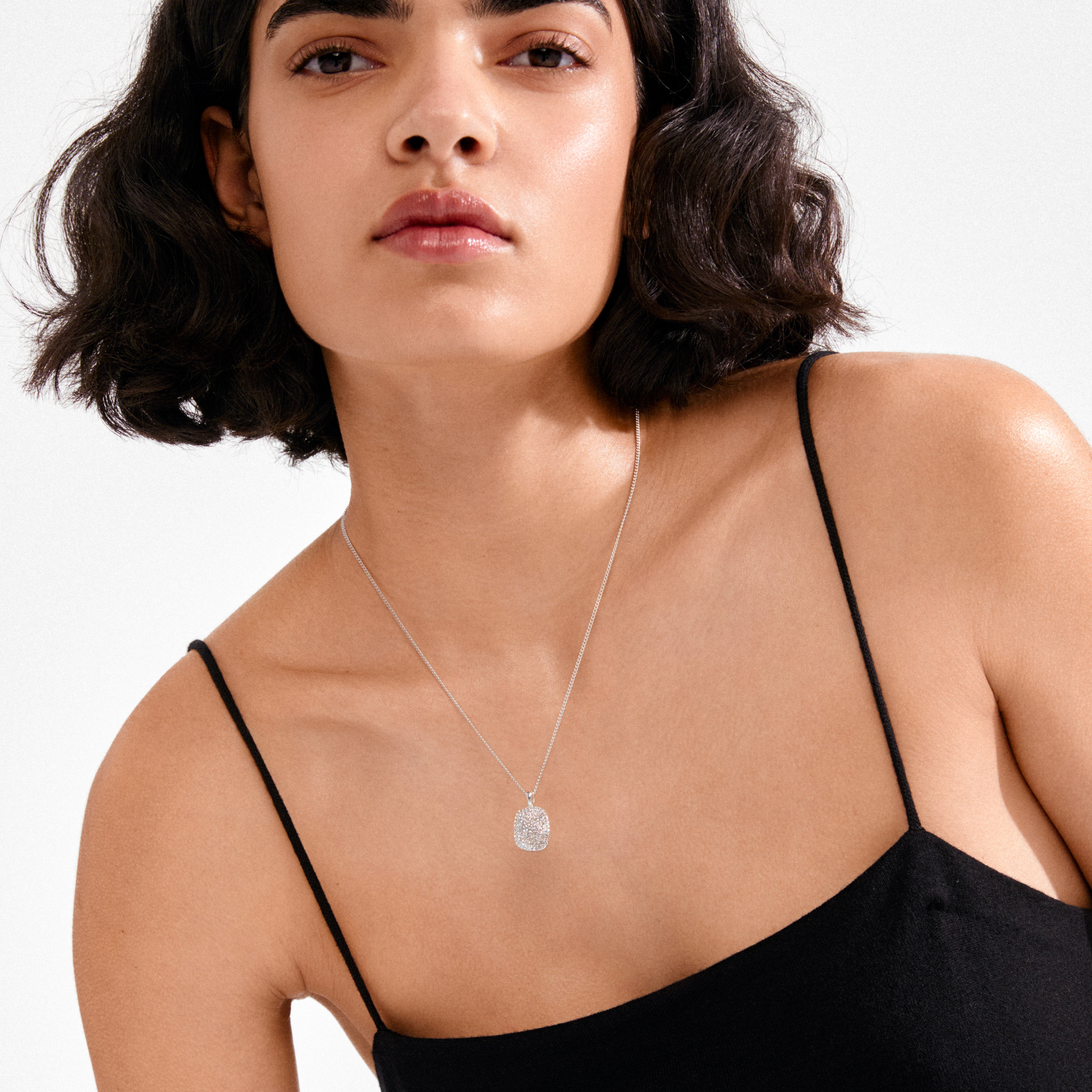Young woman wearing the EMBER necklace silver-plated by Pilgrim, featuring a sparkling pavé-set rectangular pendant on a delicate silver chain, elegantly accentuating her neckline.