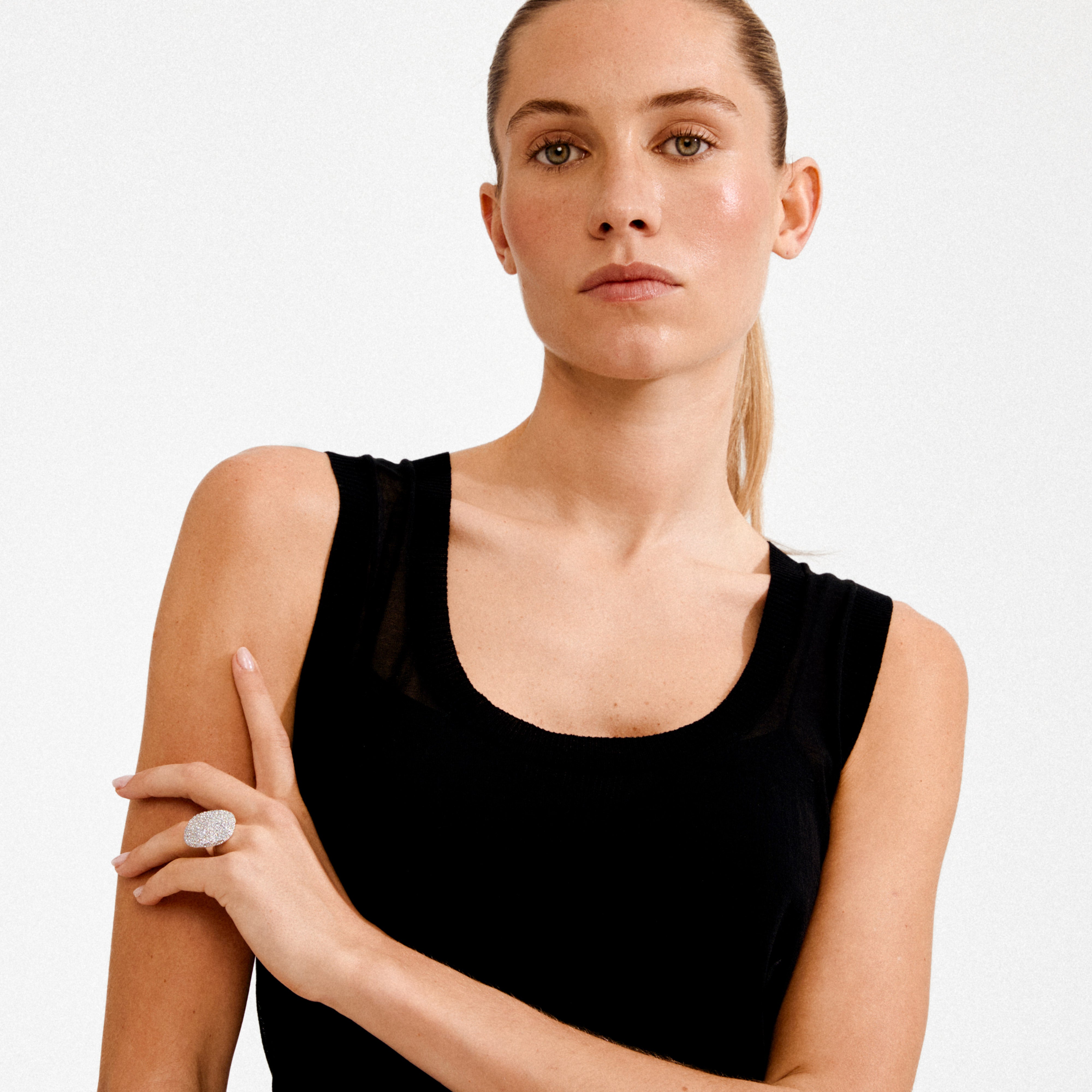 Young woman wearing the EMBER ring, a silver-plated piece with a crystal-encrusted square centrepiece, showcasing its bold, sculptural design on her right middle finger.