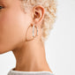 Close-up of a person's ear wearing Pilgrim's silver-plated EMBER hoop earring, showcasing its sleek, wavy design for versatile, effortless style.