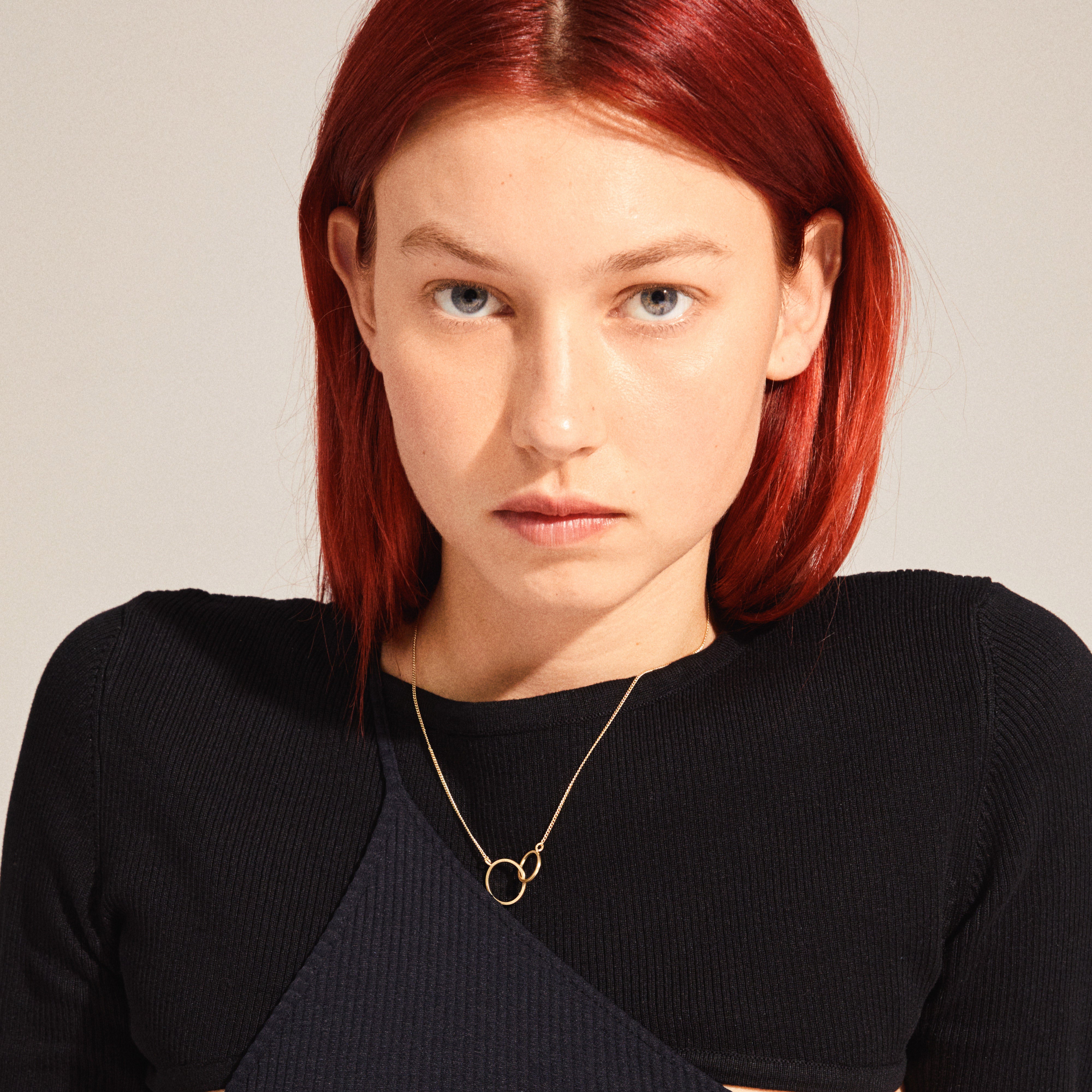 HARPER necklace gold-plated with intertwined rings pendant, worn by a red-haired woman, showcasing its elegant design and symbolic connection.