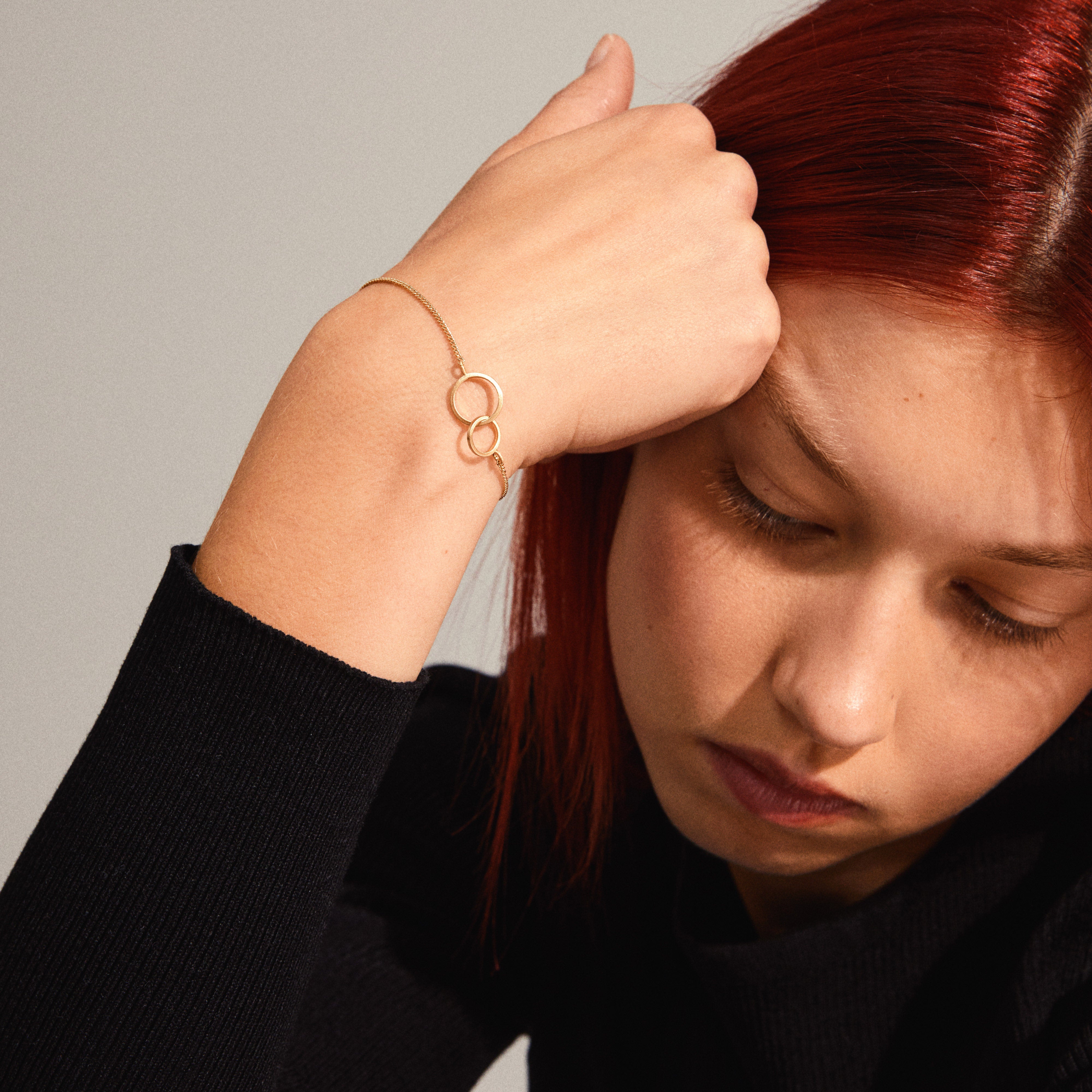 HARPER bracelet gold-plated featuring two intertwined rings, worn by a woman with red hair, showcasing its elegant design and timeless appeal.