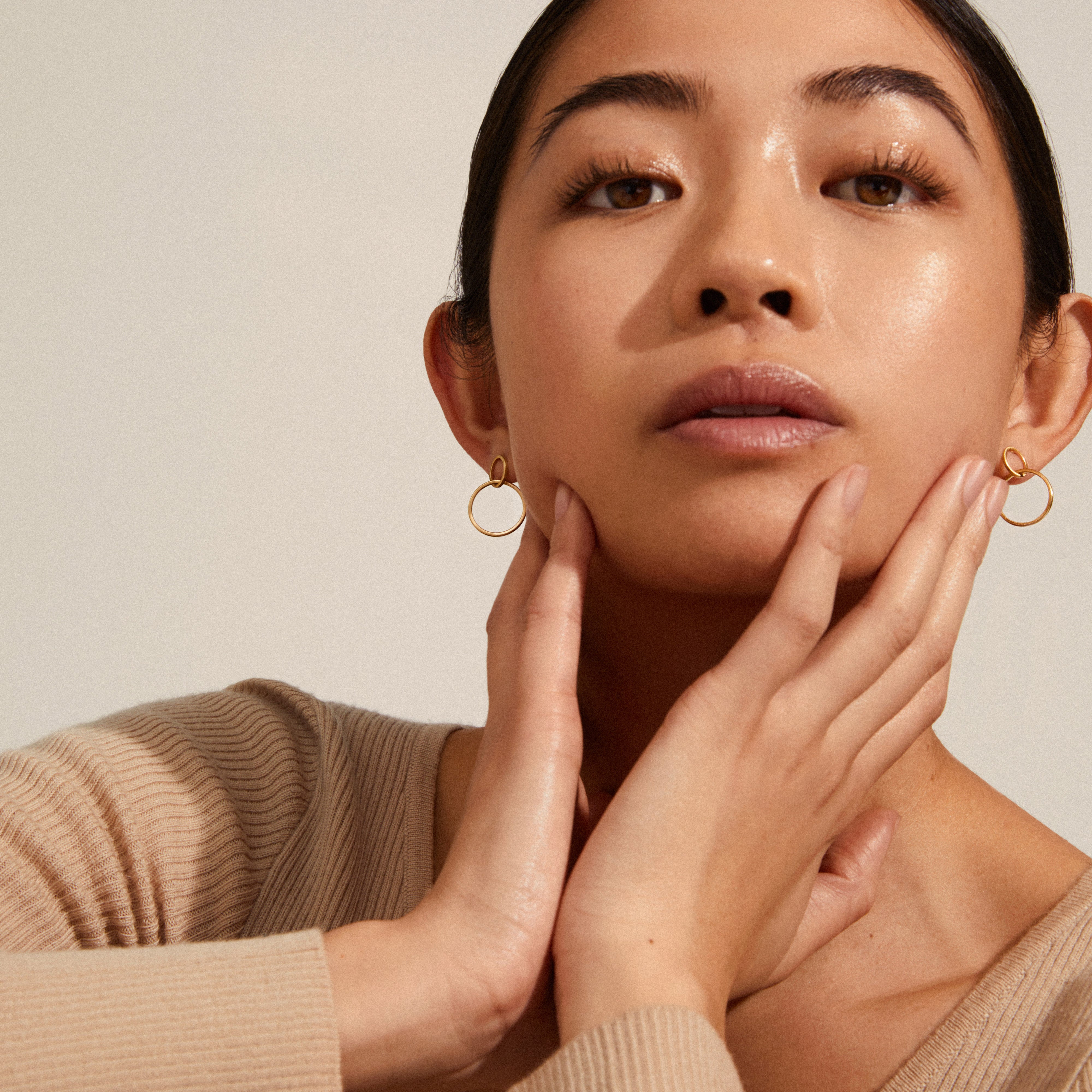 Close-up of a woman wearing HARPER earrings, featuring gold-plated satin-matte intertwined rings, highlighting Danish elegance and Nordic design.