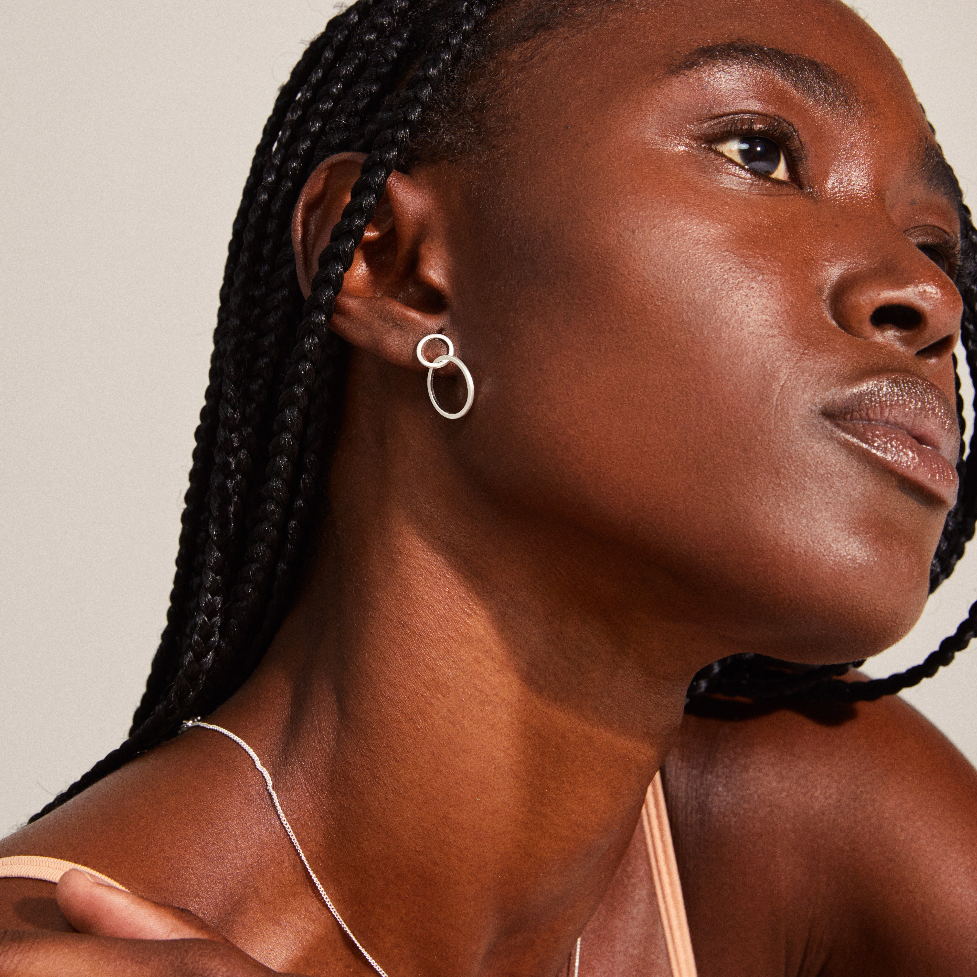 Close-up of a woman wearing the HARPER earrings, featuring two satin-matte intertwined silver-plated rings, showcasing classic Nordic design.