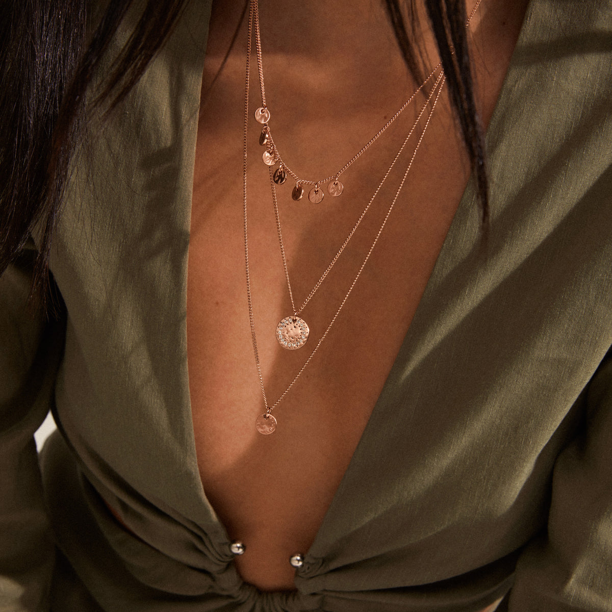 Close-up of the ARDEN 3-in-1 crystal necklace, rose gold-plated, featuring layered chains with disc charms and a textured pendant, embodying a unique, feminine design.