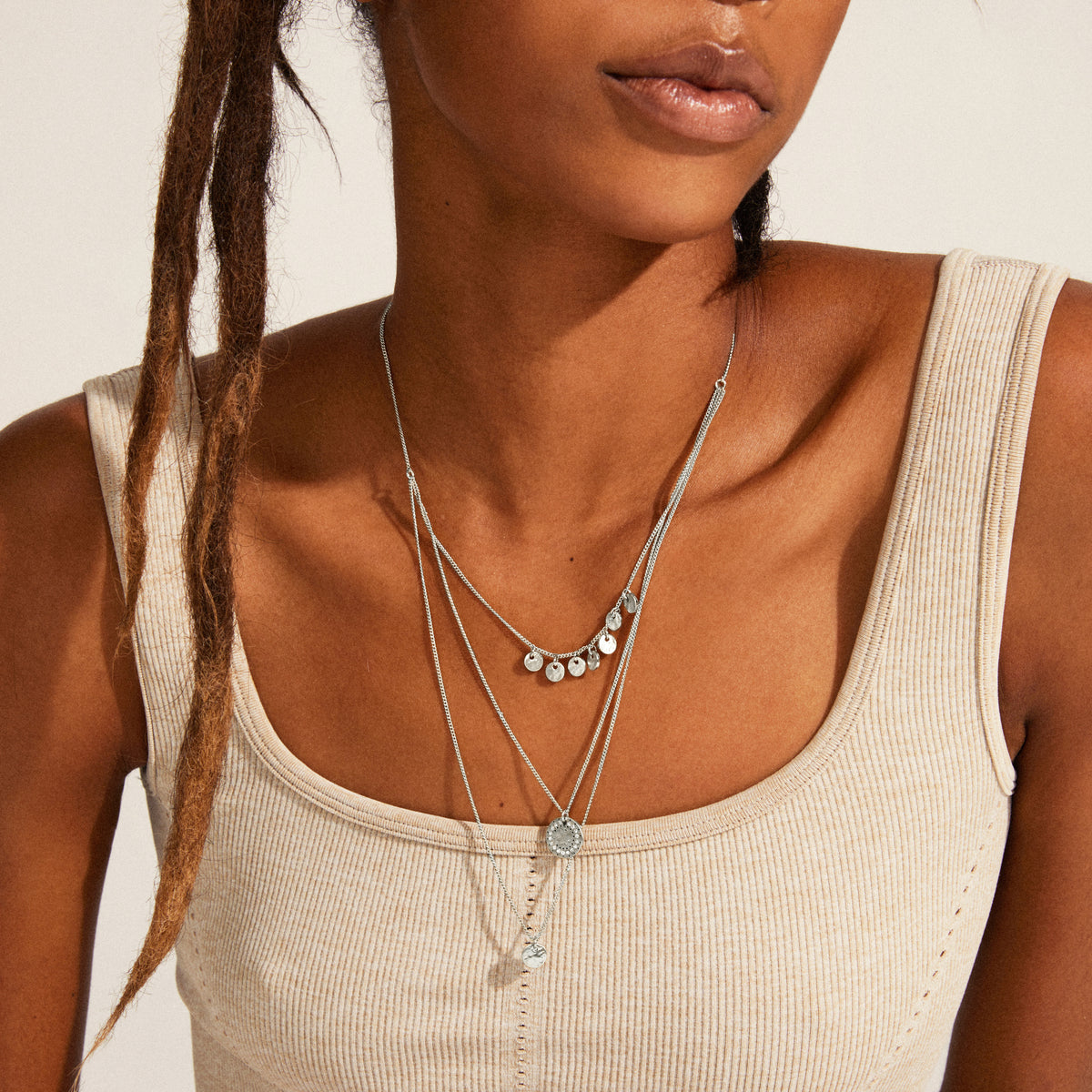 Close-up of ARDEN 3-in-1 crystal necklace, featuring silver-plated amulets with rustic finishes and sparkling crystals, nestled beautifully on a person's décolletage.