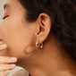 Close-up of a woman wearing ZION organic shaped medium gold-plated hoops, showcasing the nature-inspired design and elegant style from Pilgrim.
