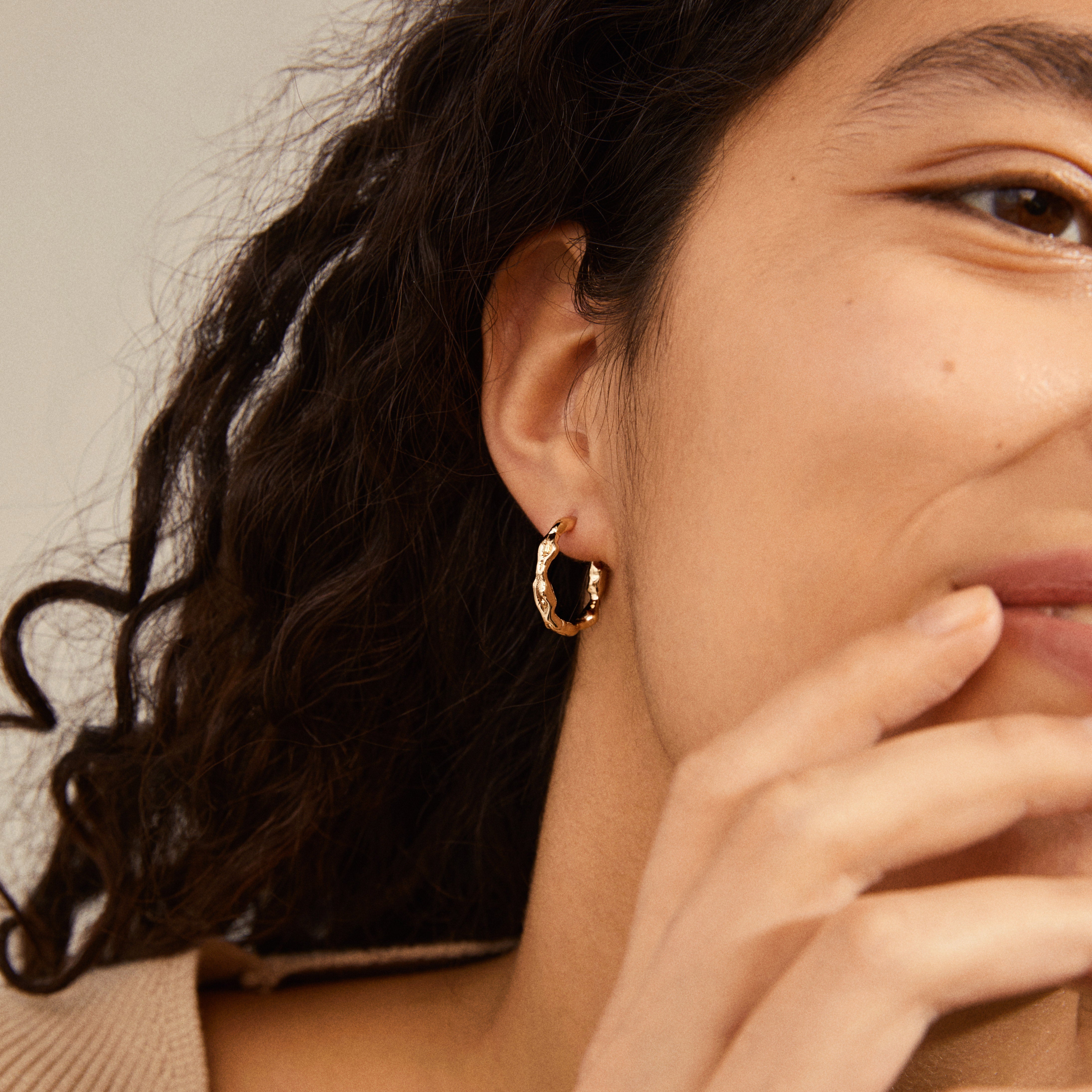 Close-up of a woman wearing Pilgrim's ZION organic-shaped medium hoops, gold-plated, showcasing their nature-inspired, elegant design.