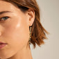 Close-up of a woman wearing Pilgrim's THANKFUL long chain gold-plated earrings, featuring organic pendants for a classy, natural look inspired by nature.