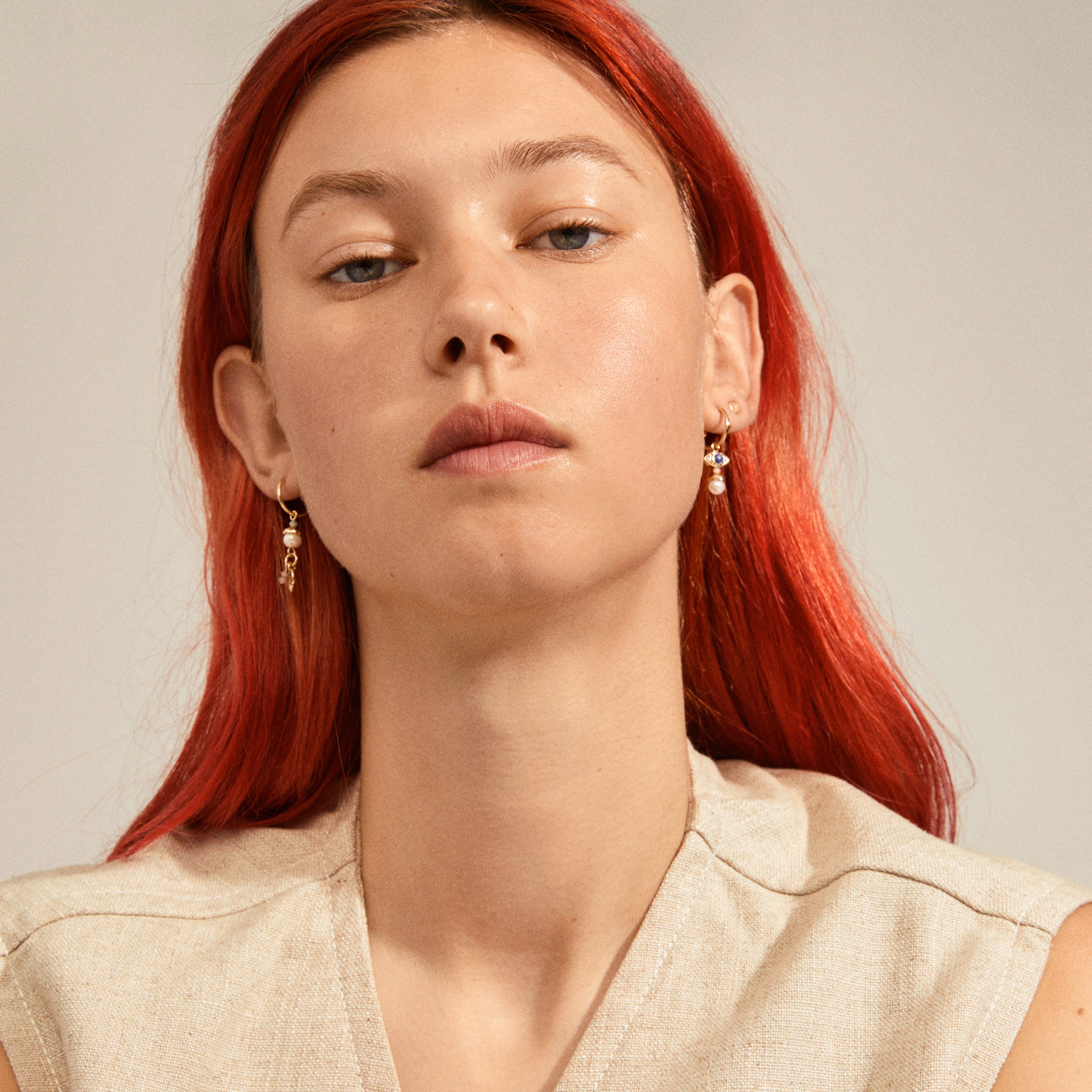 Woman with red hair wearing the THANKFUL asymmetric 2-in-1 set earrings gold-plated, featuring quirky semi-hoops with symbol pendants and fine ear studs.