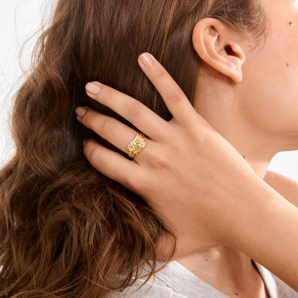 Close-up of a hand wearing the BLOSSOM organic-shaped, gold-plated ring with unfinished edges, highlighting its bold, handcrafted texture and shine.
