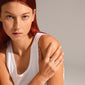 Woman wearing a white tank top showcases Pilgrim's BLOSSOM organic-shaped silver-plated ring, featuring handcrafted, irregular design, emphasizing eco-friendly, recycled materials.