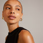 ECHO hoop earrings gold-plated, featuring a romantic flower design, worn by a woman looking to the side, showcasing elegance and classic beauty.