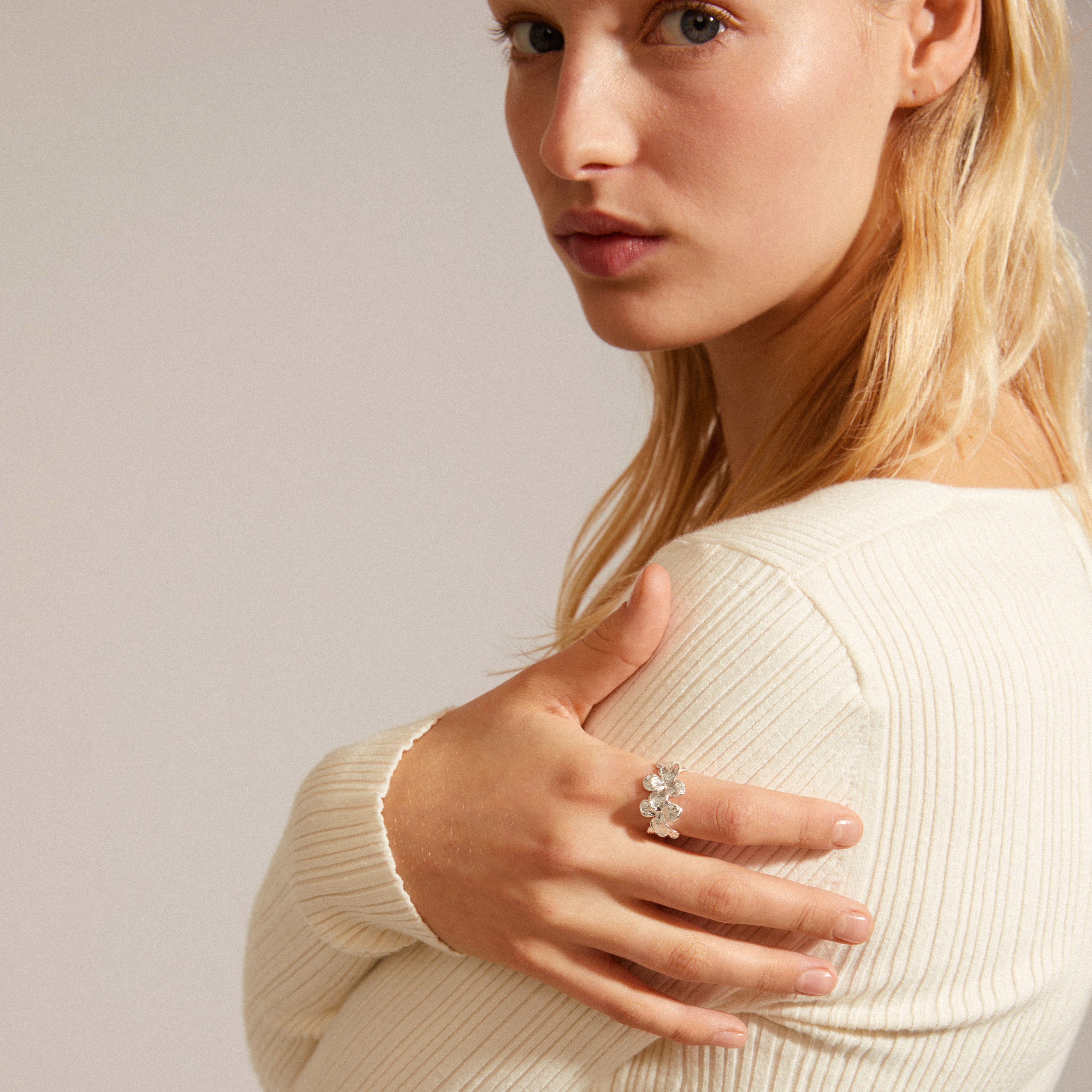 Woman wearing Pilgrim's ECHO ring, silver-plated with floral design, highlighting natural beauty and authenticity. Close-up emphasizes the ring's shiny finish.